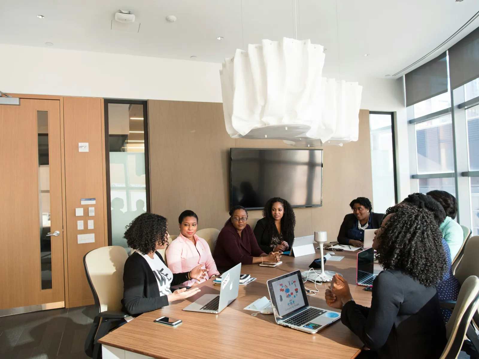 a group of people sitting around a table with laptops