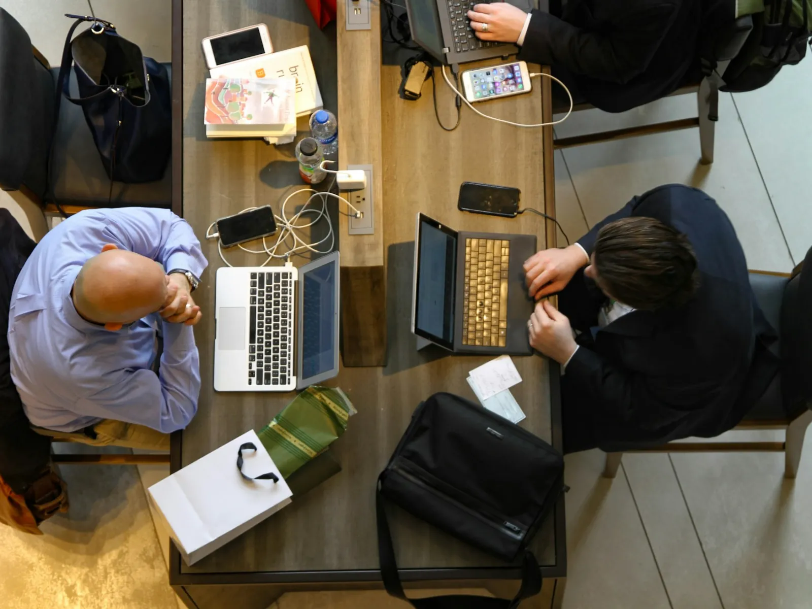 a couple of people sitting at a table with laptops