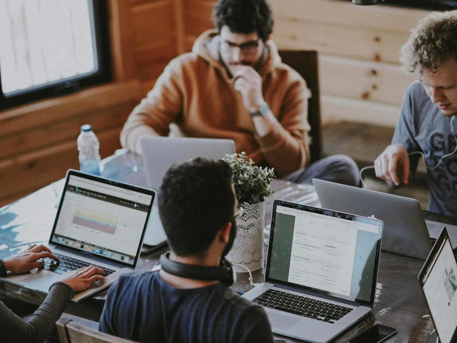 a group of people sitting at a table with laptops