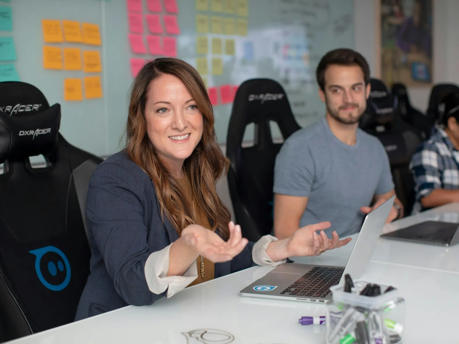 a woman and a man sitting at a table with laptops
