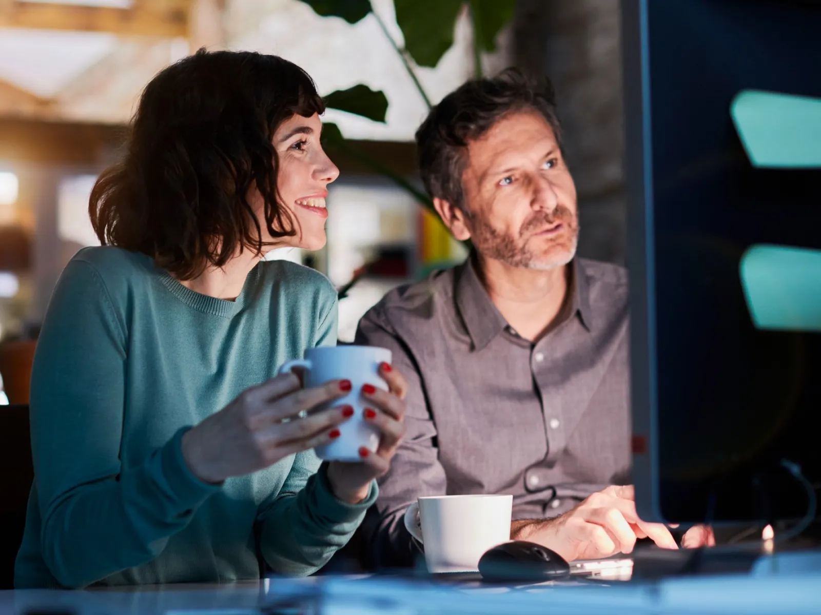a man and a woman sitting at a table with a computer