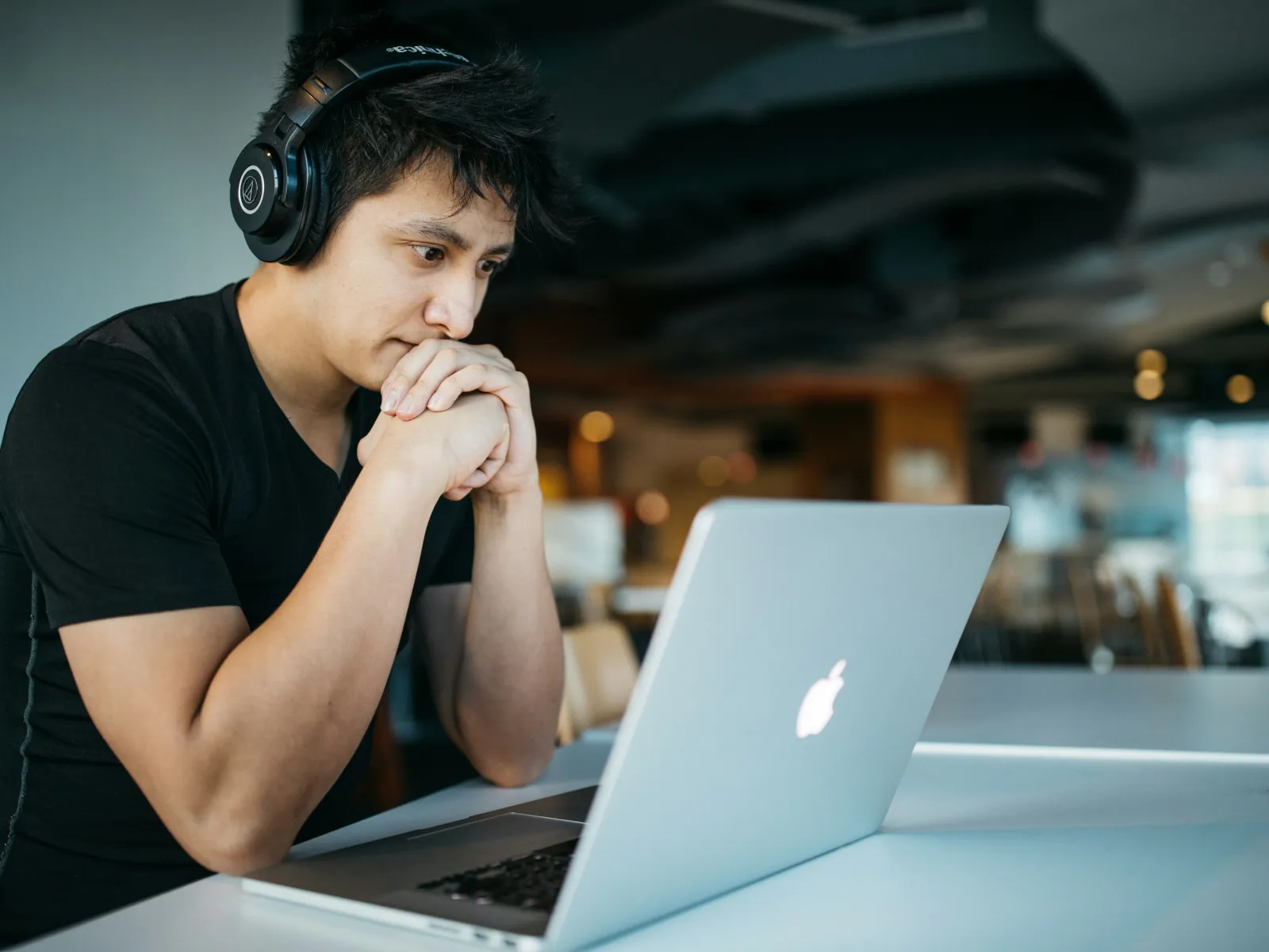 a person wearing headphones and sitting at a table with a laptop
