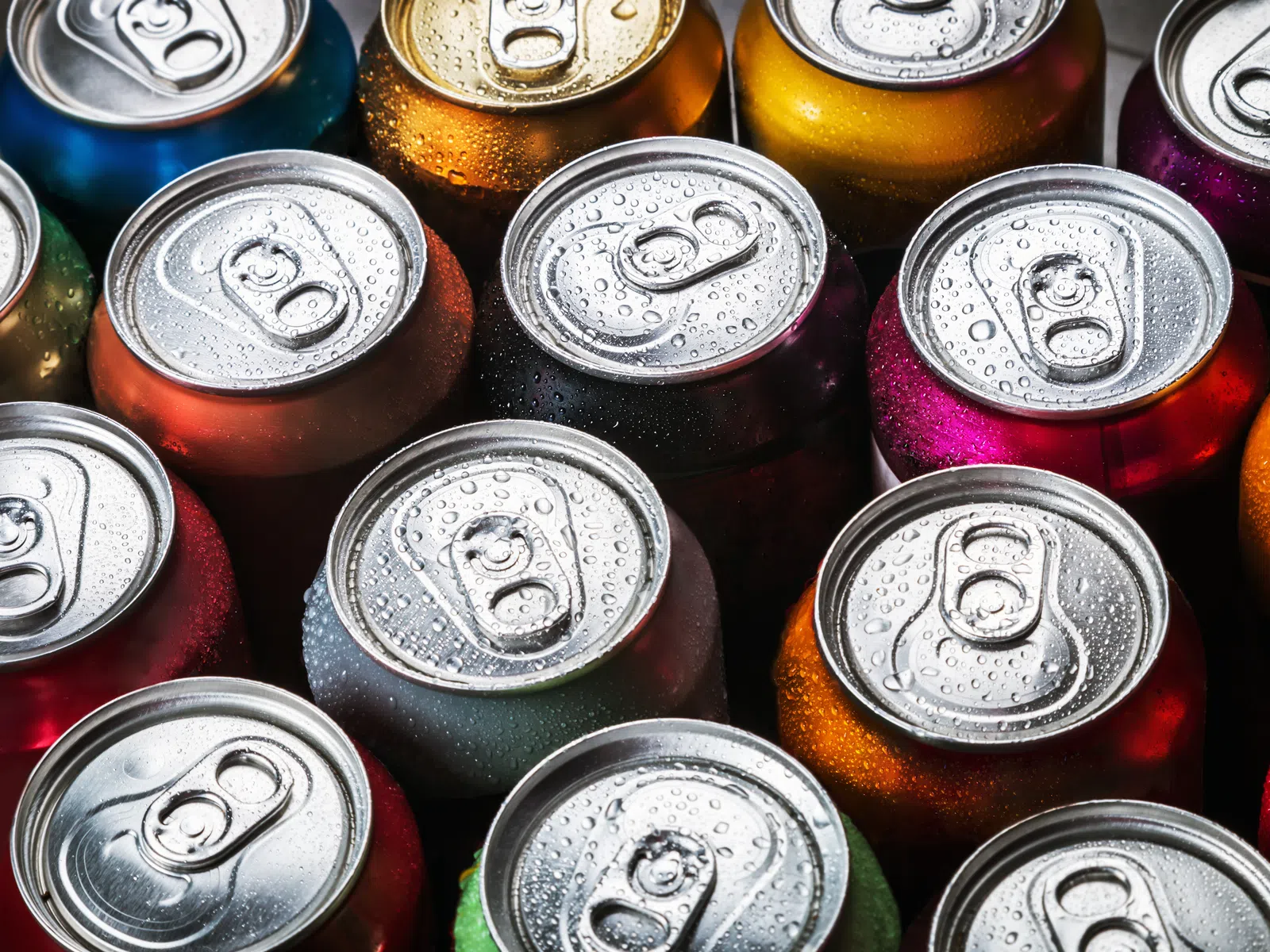 Top view of colorful aluminum drink cans with water droplets in close-up, showcasing vibrant beverage containers.