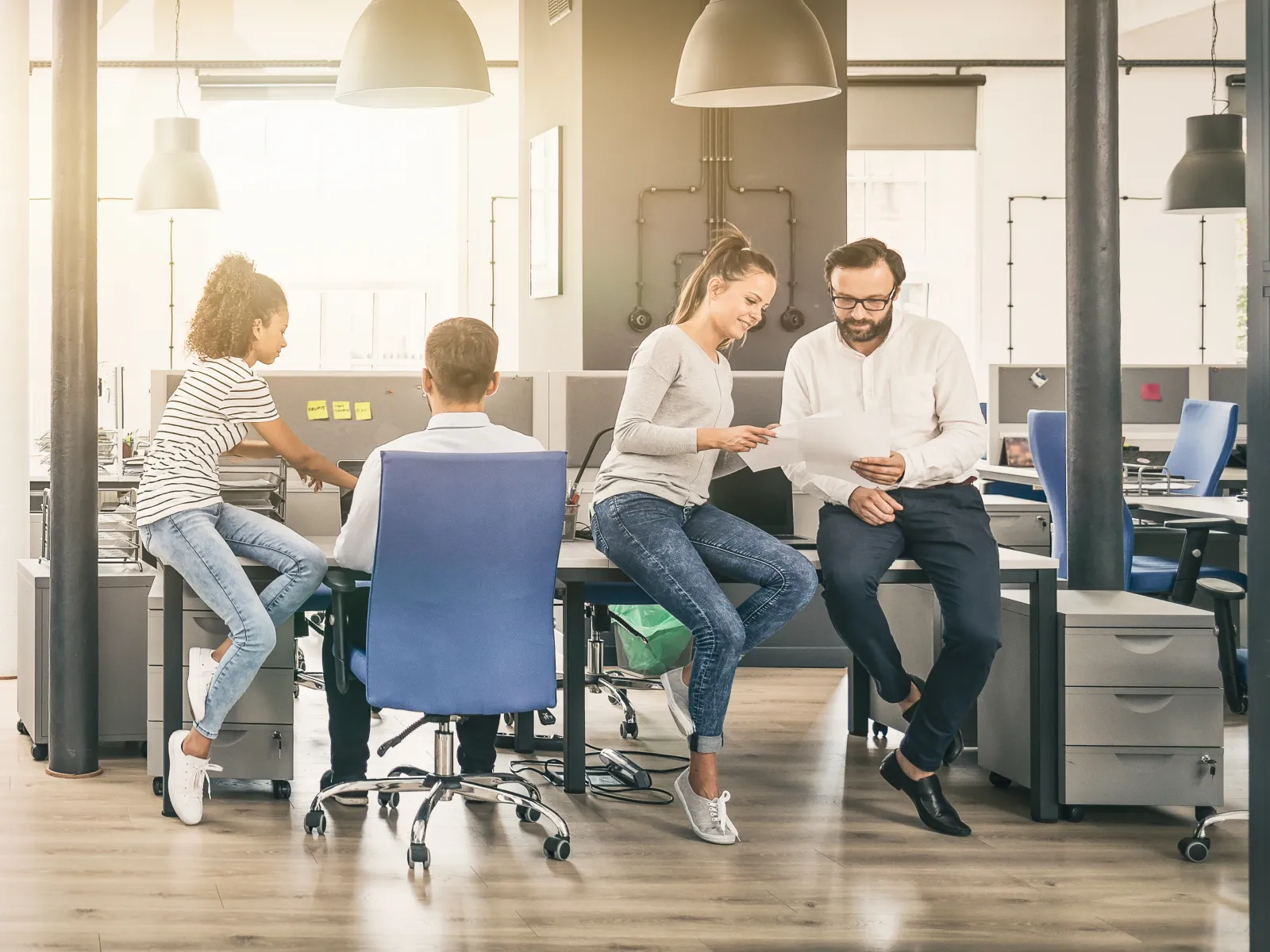 Busy modern office with diverse team collaborating and working at desks in a bright open workspace.