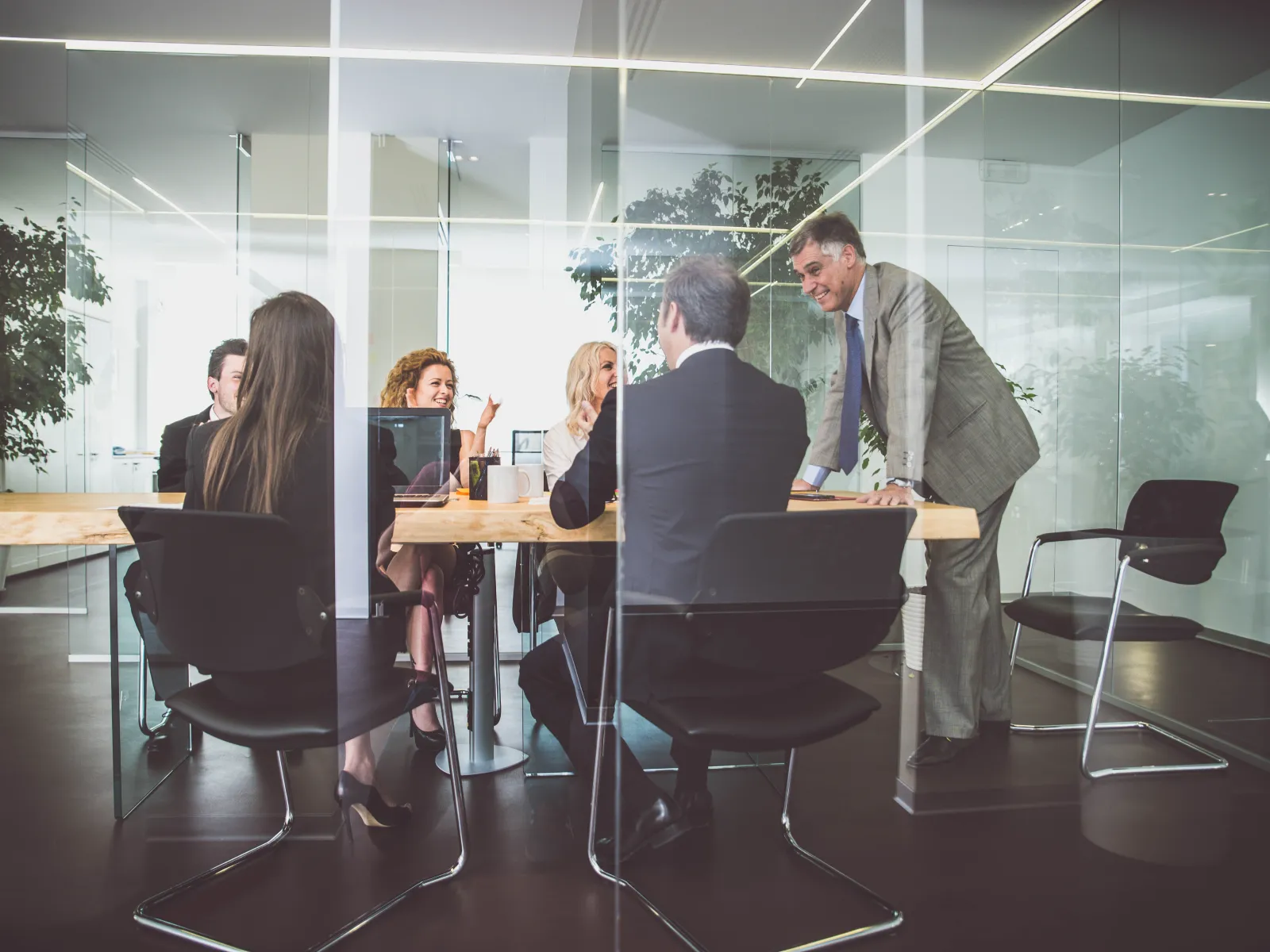 Business team engaged in a meeting around a conference table in a modern glass office room.