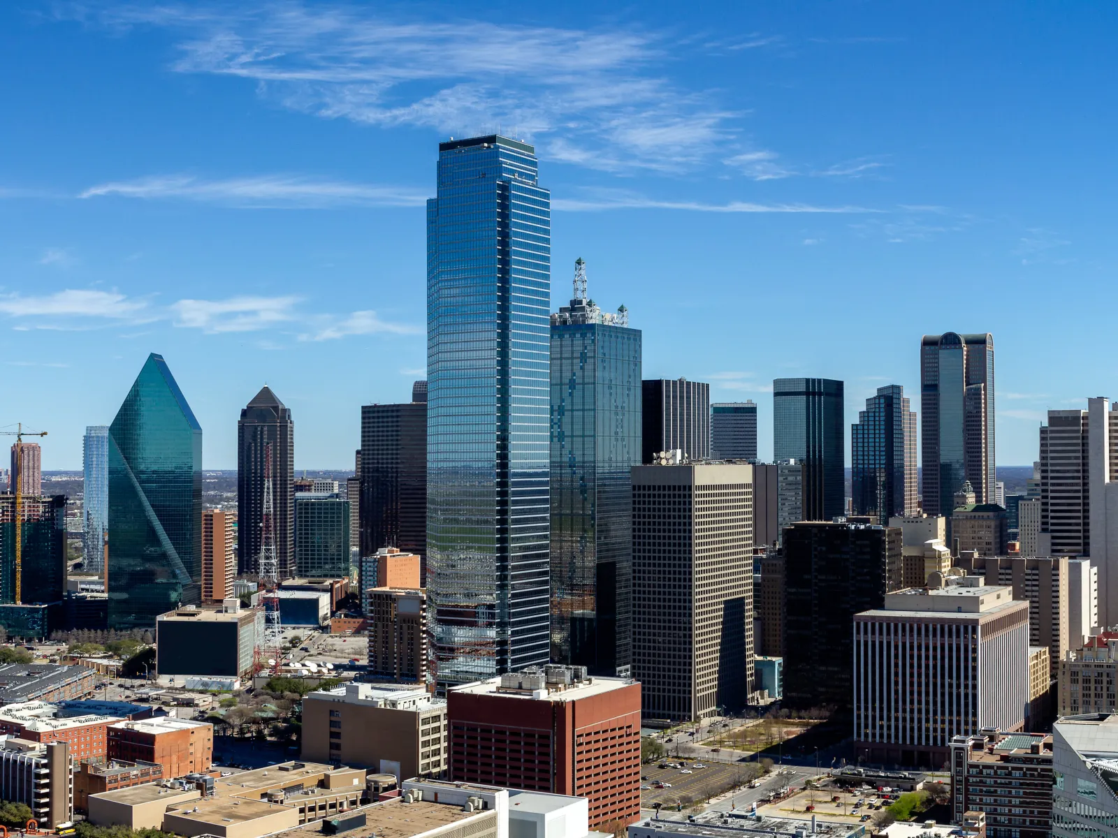 Clear daytime view of Dallas skyline with prominent skyscrapers under a bright blue sky.