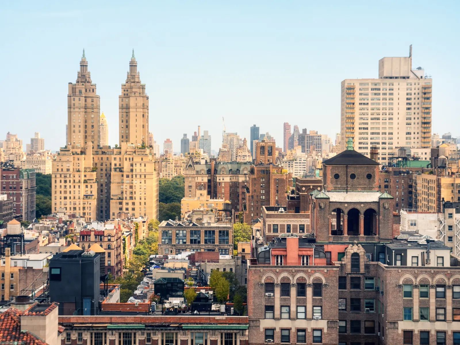 City skyline with tall historic and modern buildings under clear blue sky during daytime