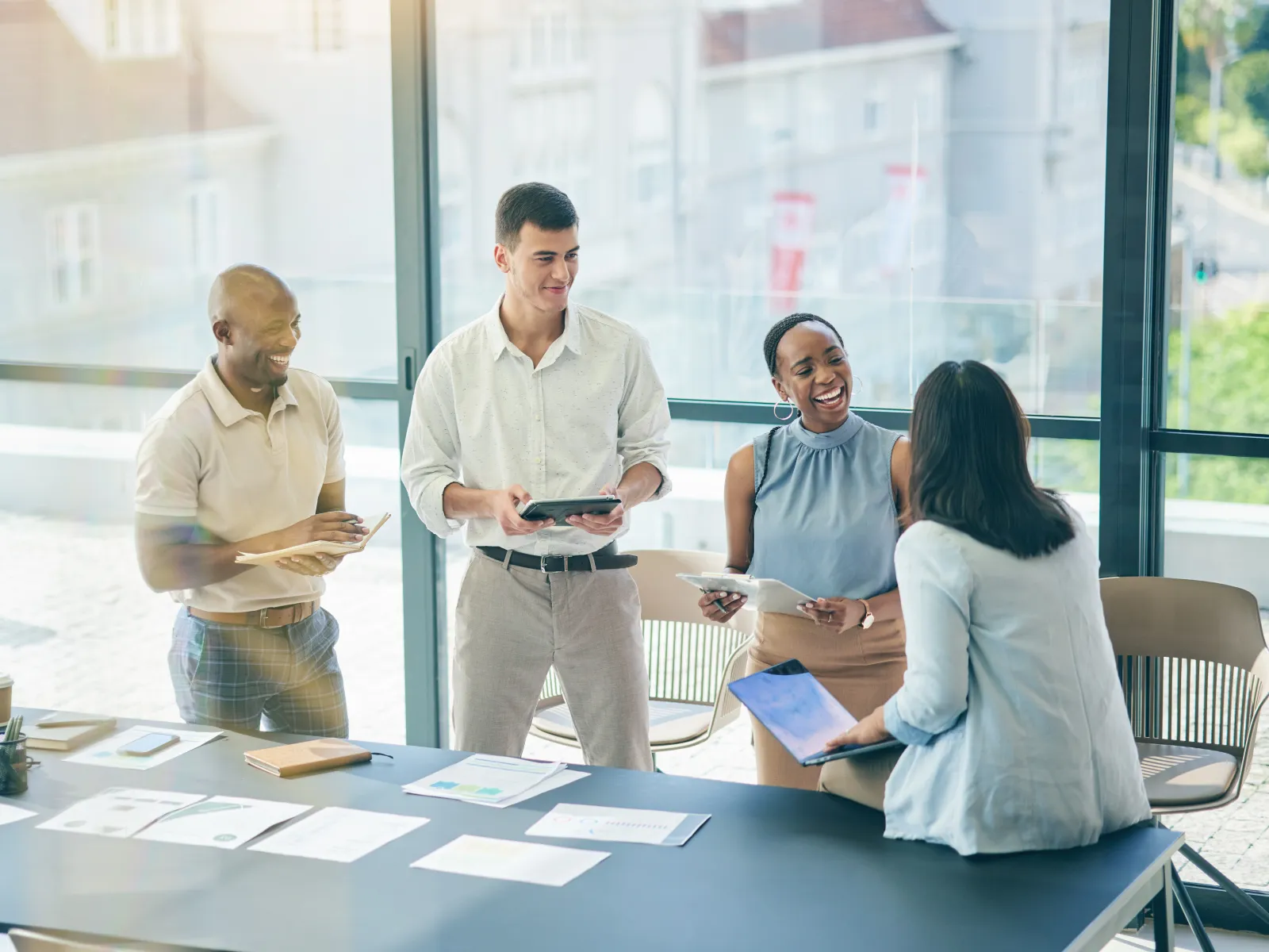 Diverse team collaborating and sharing ideas in a bright modern office with documents and digital devices.