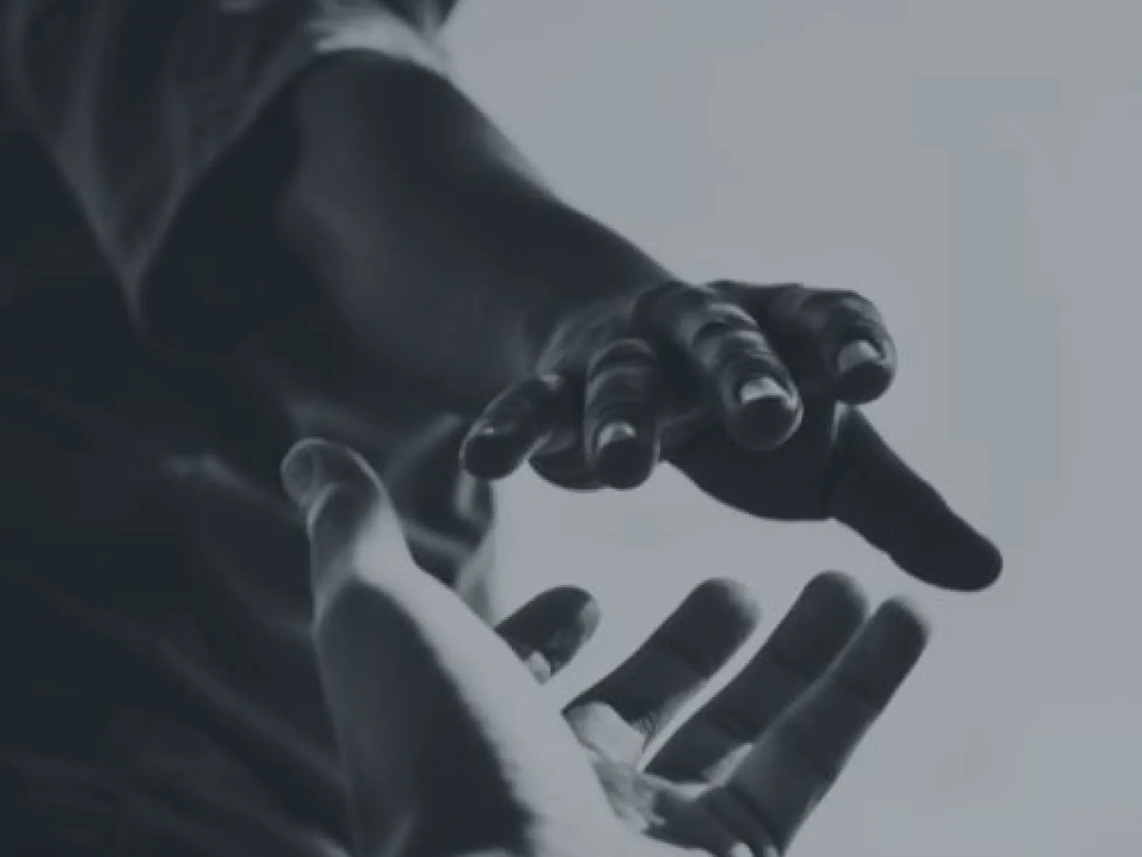 Two hands reaching towards each other symbolizing support and connection in black and white.