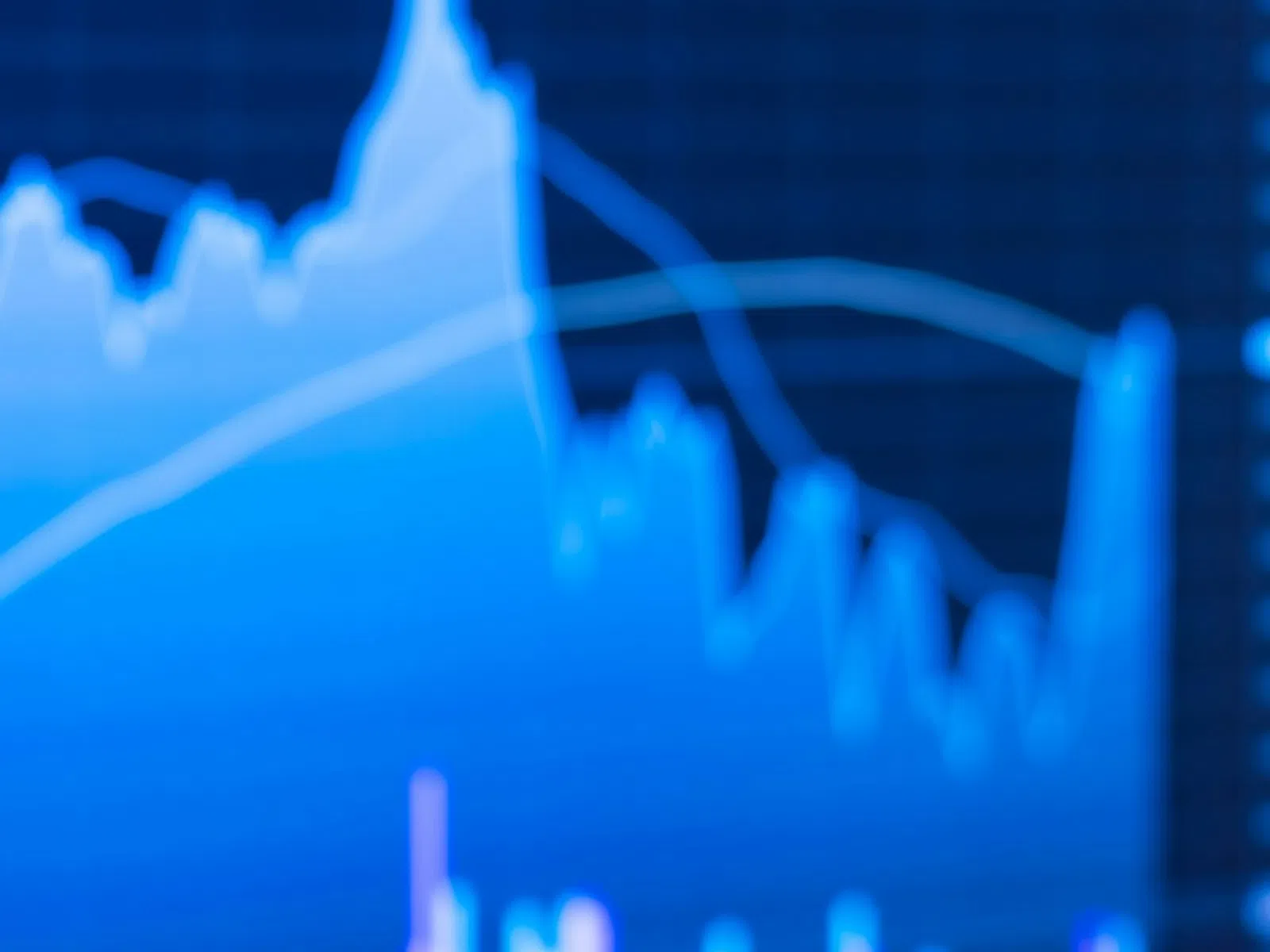 Hand holding smartphone displaying financial stock chart with graphs and trading data on blue background.