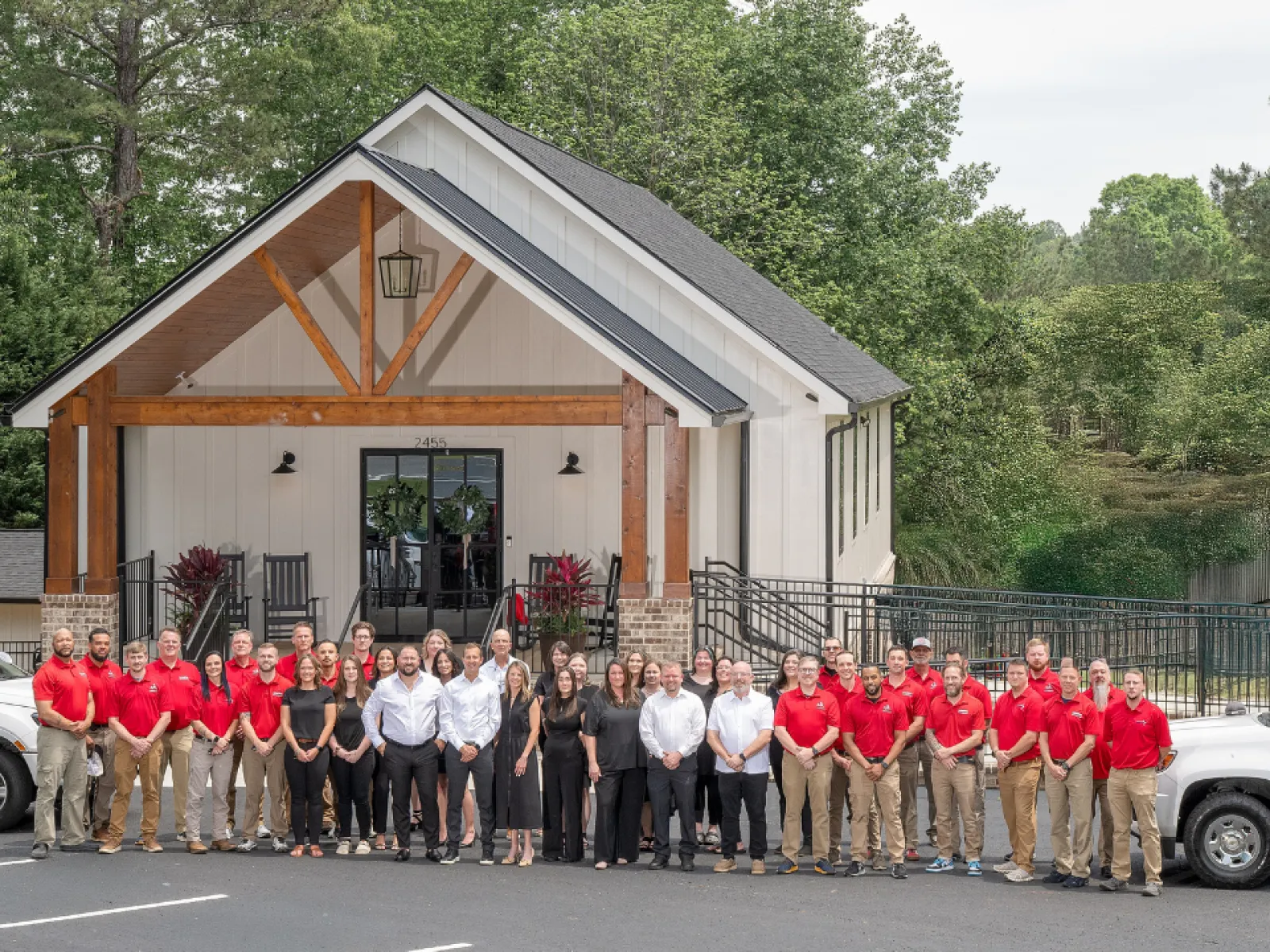 Large group of LunsPro professionals standing in front of a modern office building with company trucks parked on both sides
