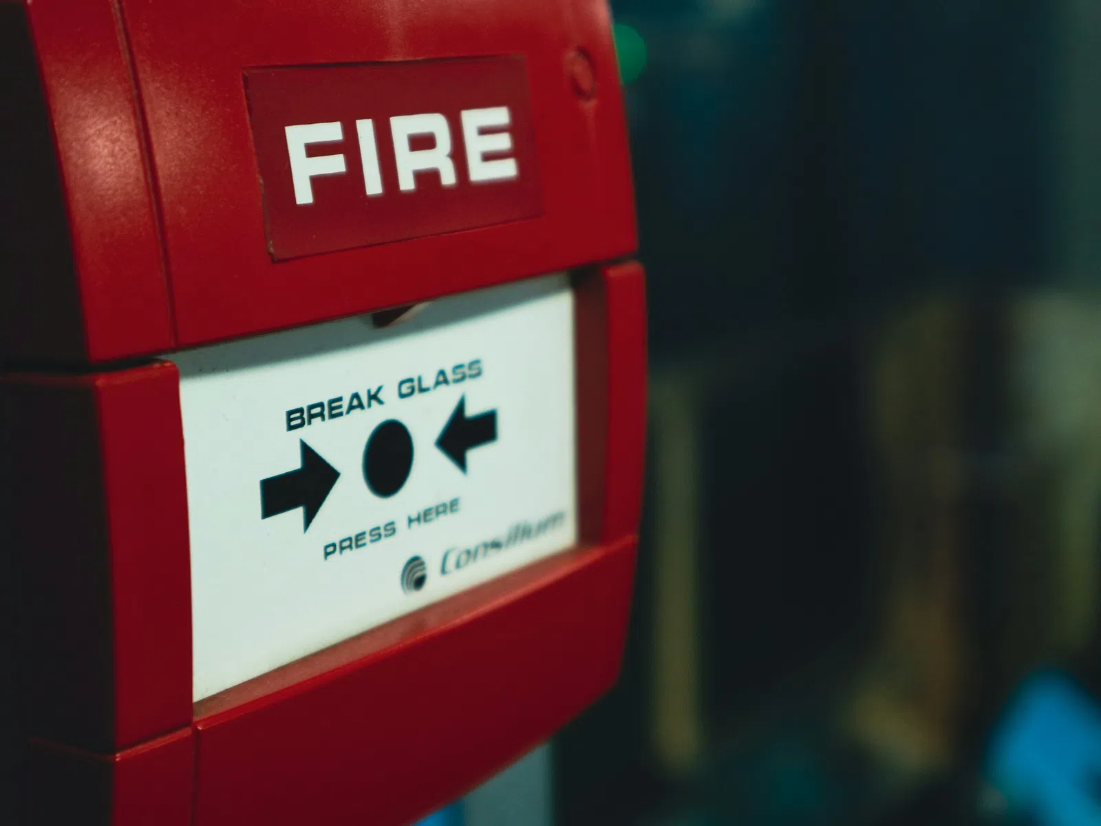Close-up of a red fire alarm with instructions to break glass and press button for emergency activation.