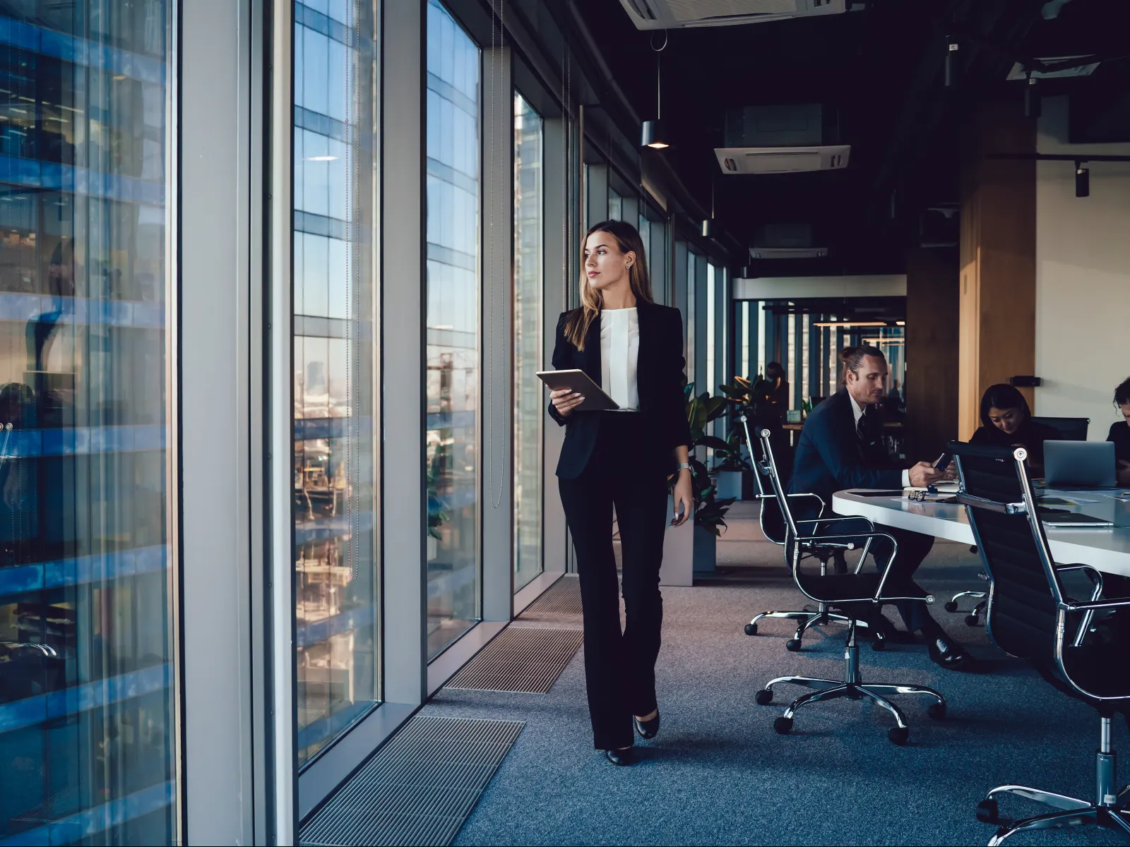 a person standing in a room with people sitting at tables and computers