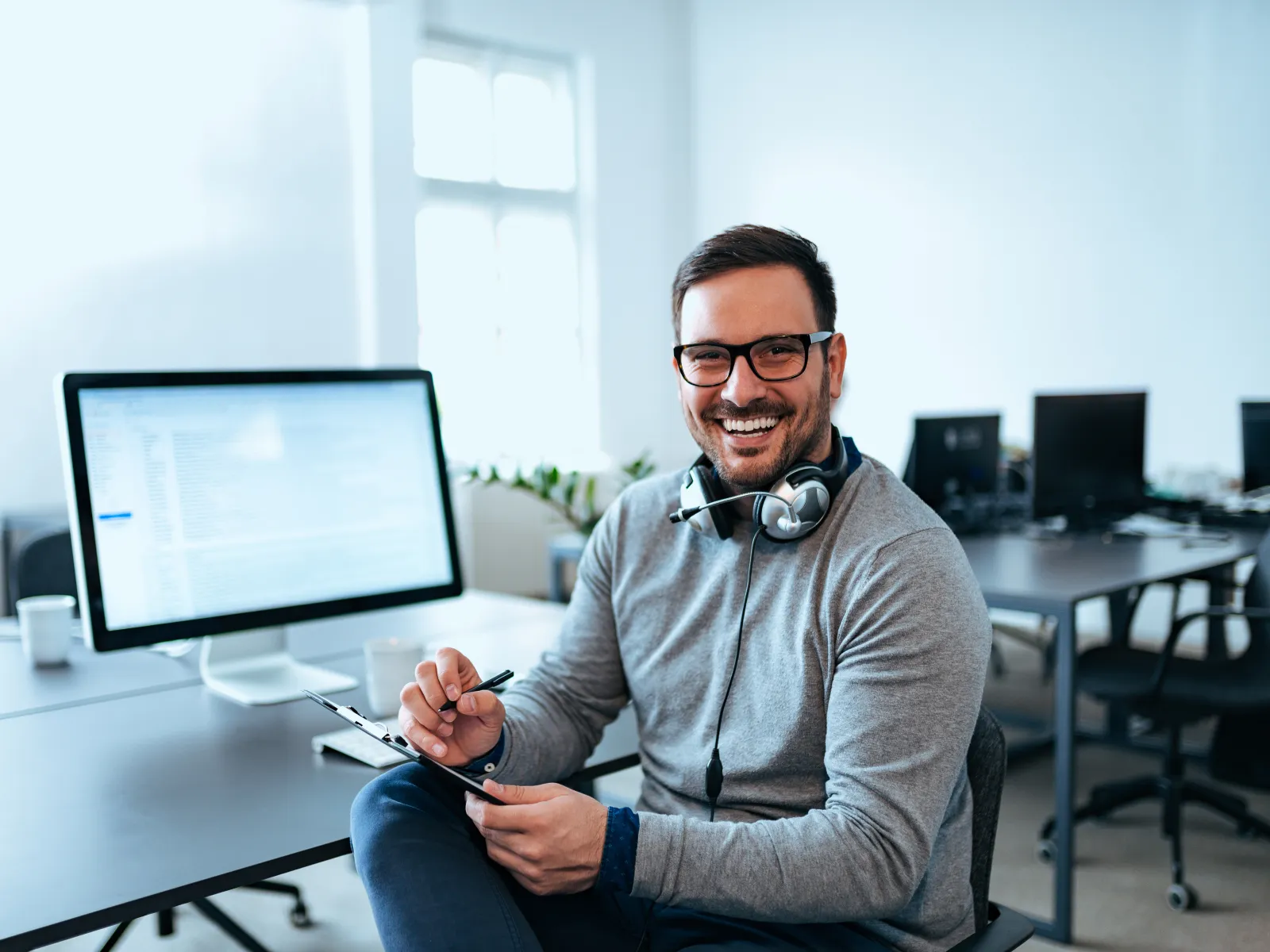 a man sitting at a desk with a computer and headphones on