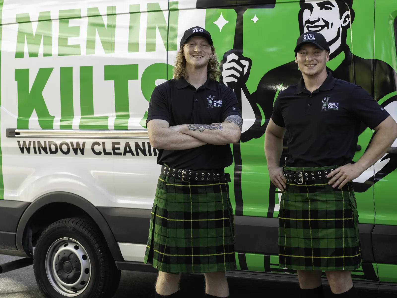 two men in kilts standing in front of a green truck