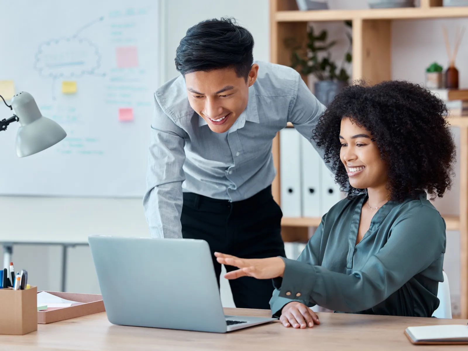 a woman showing a man something on the laptop