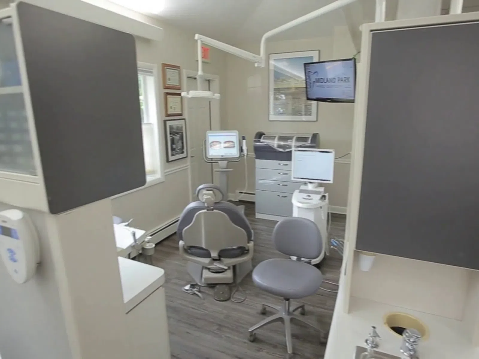 Modern dental clinic room with dental chair, monitor, equipment, and bright natural lighting