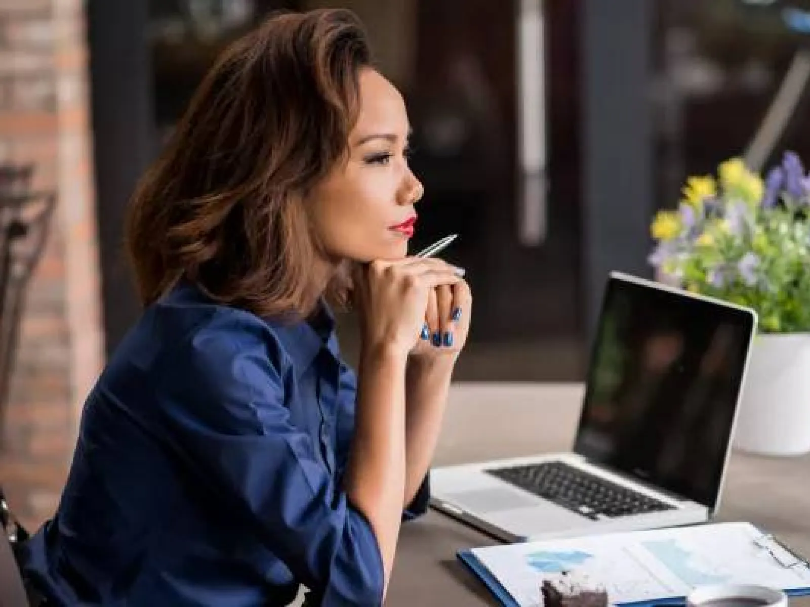 a woman sitting at a table with a laptop and a pen