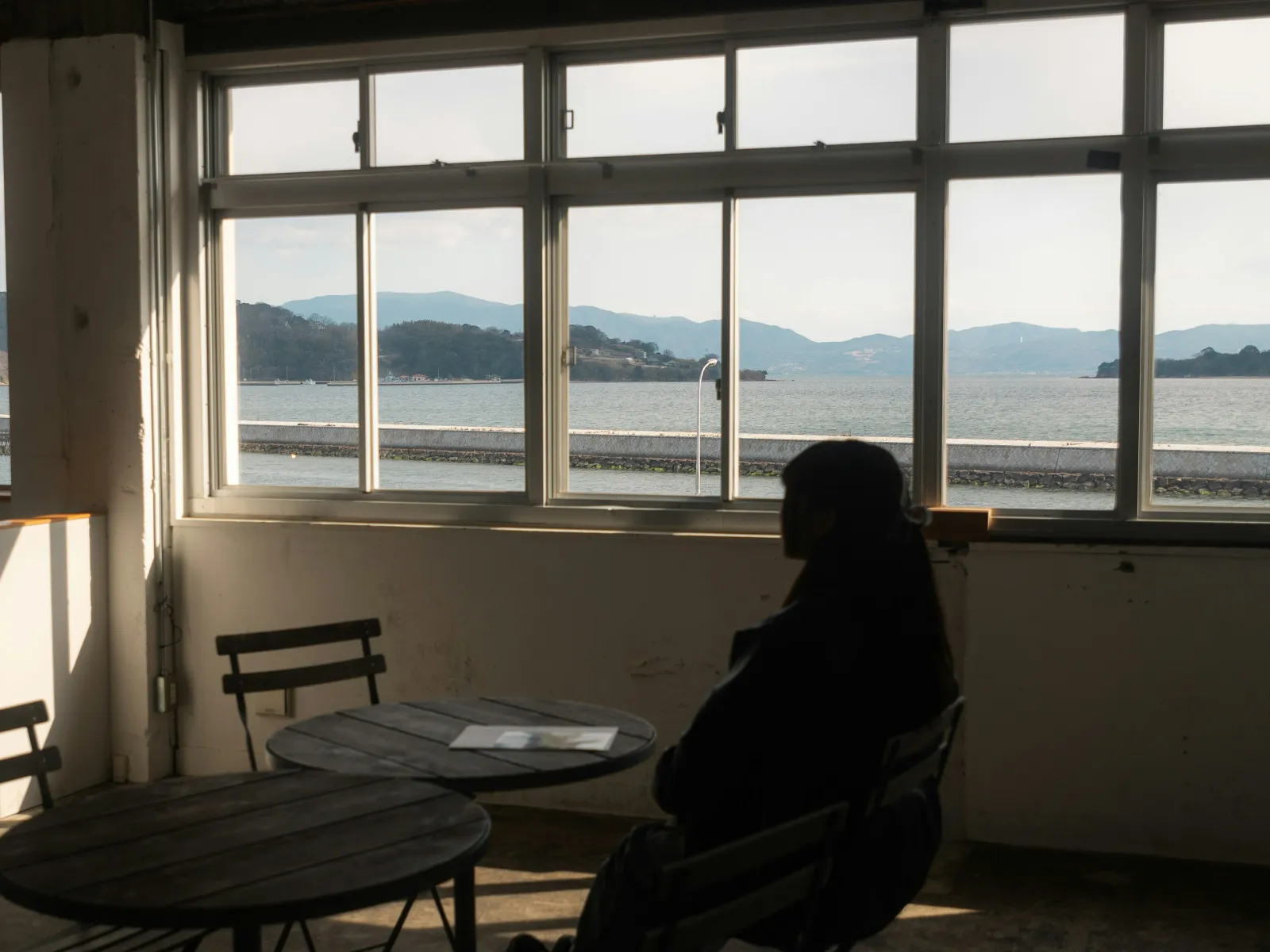 a person sitting at a table looking out a window