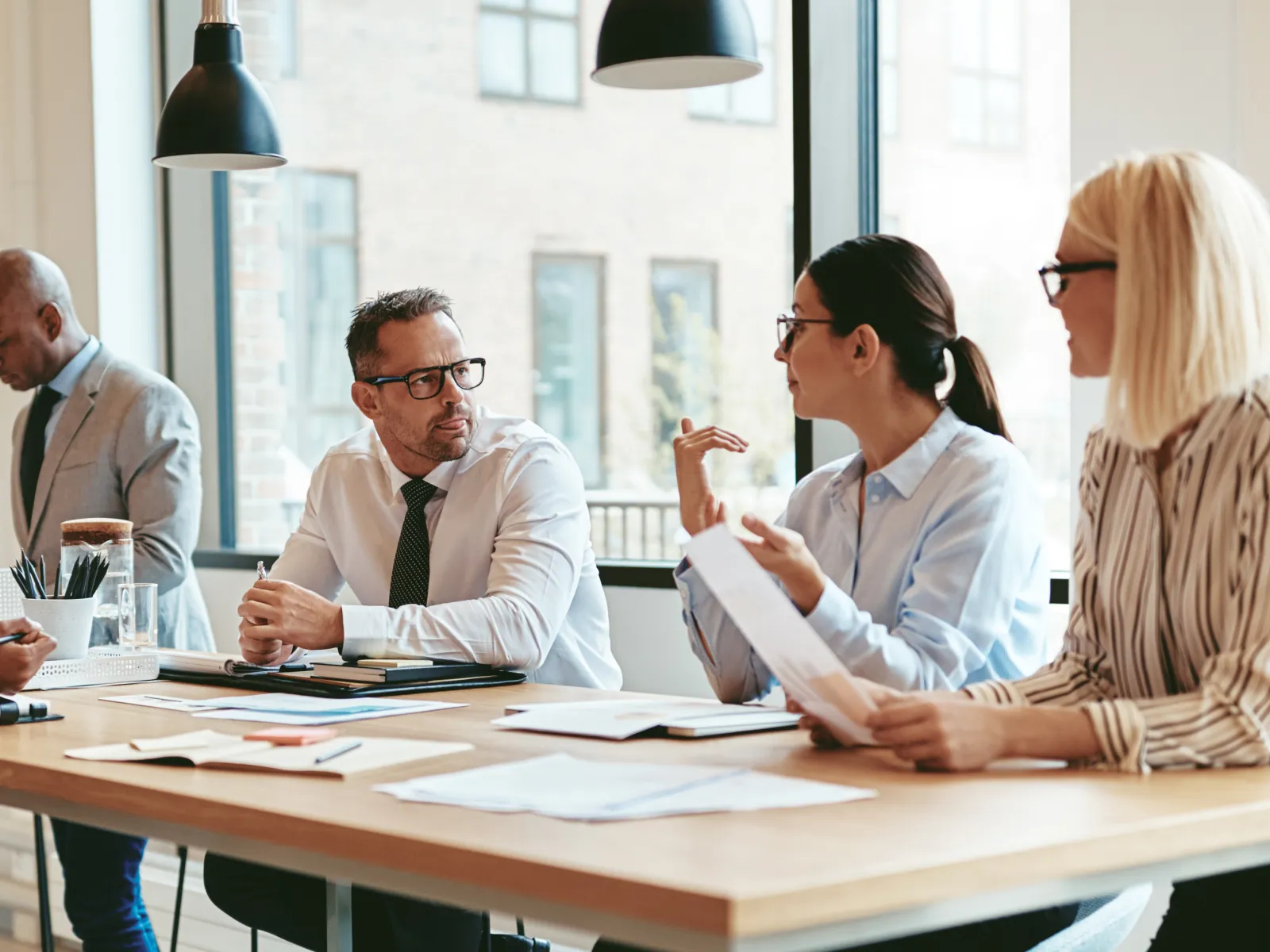 Diverse business team engaged in a meeting around a wooden table in a bright modern office.