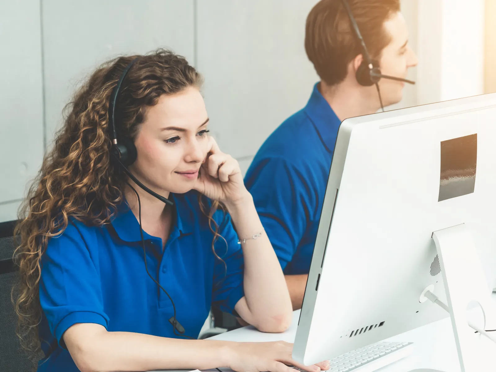 Customer service team wearing headsets working on computers in a bright call center environment