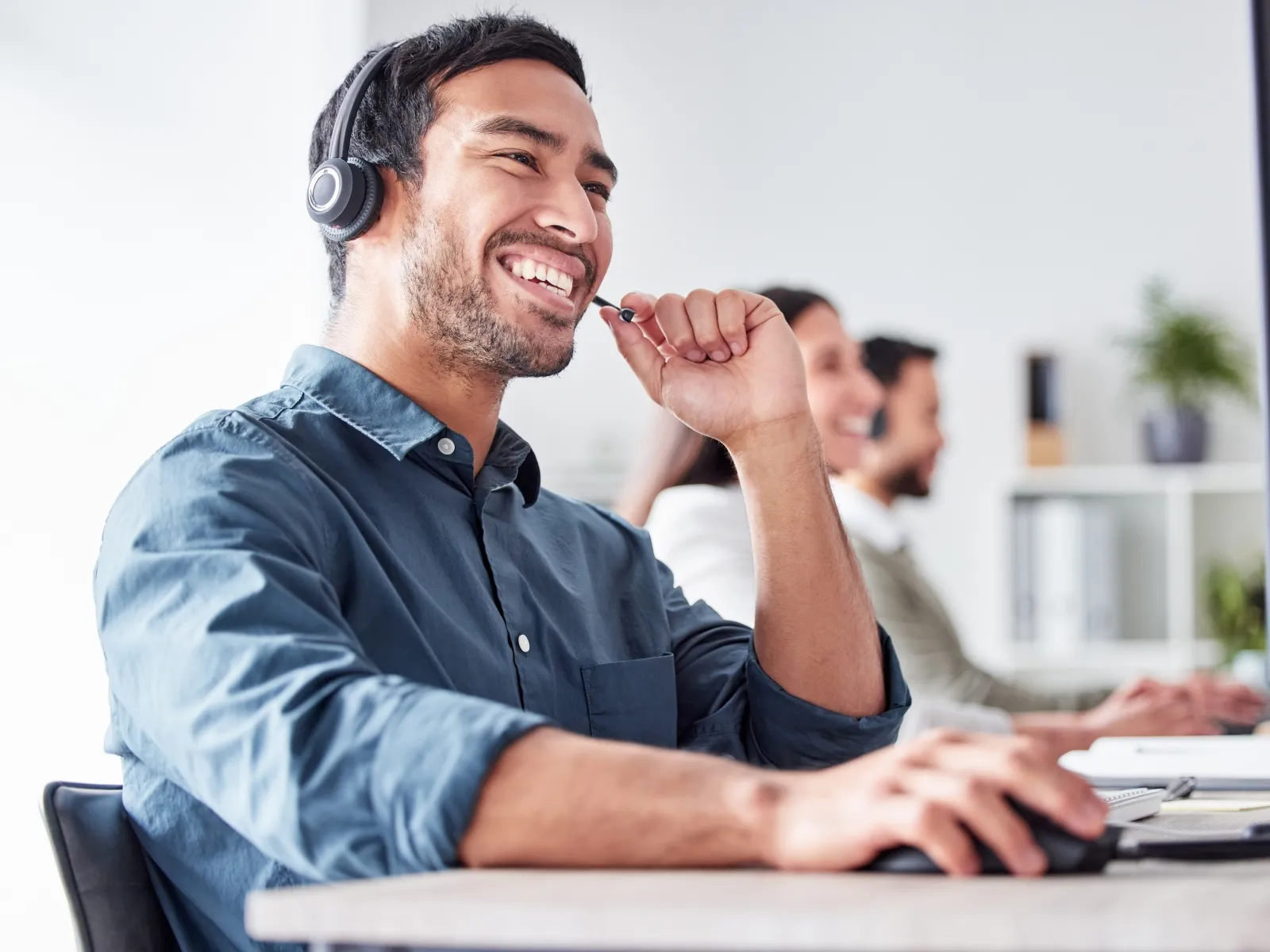 Smiling customer service representative wearing headset working on computer in modern office environment