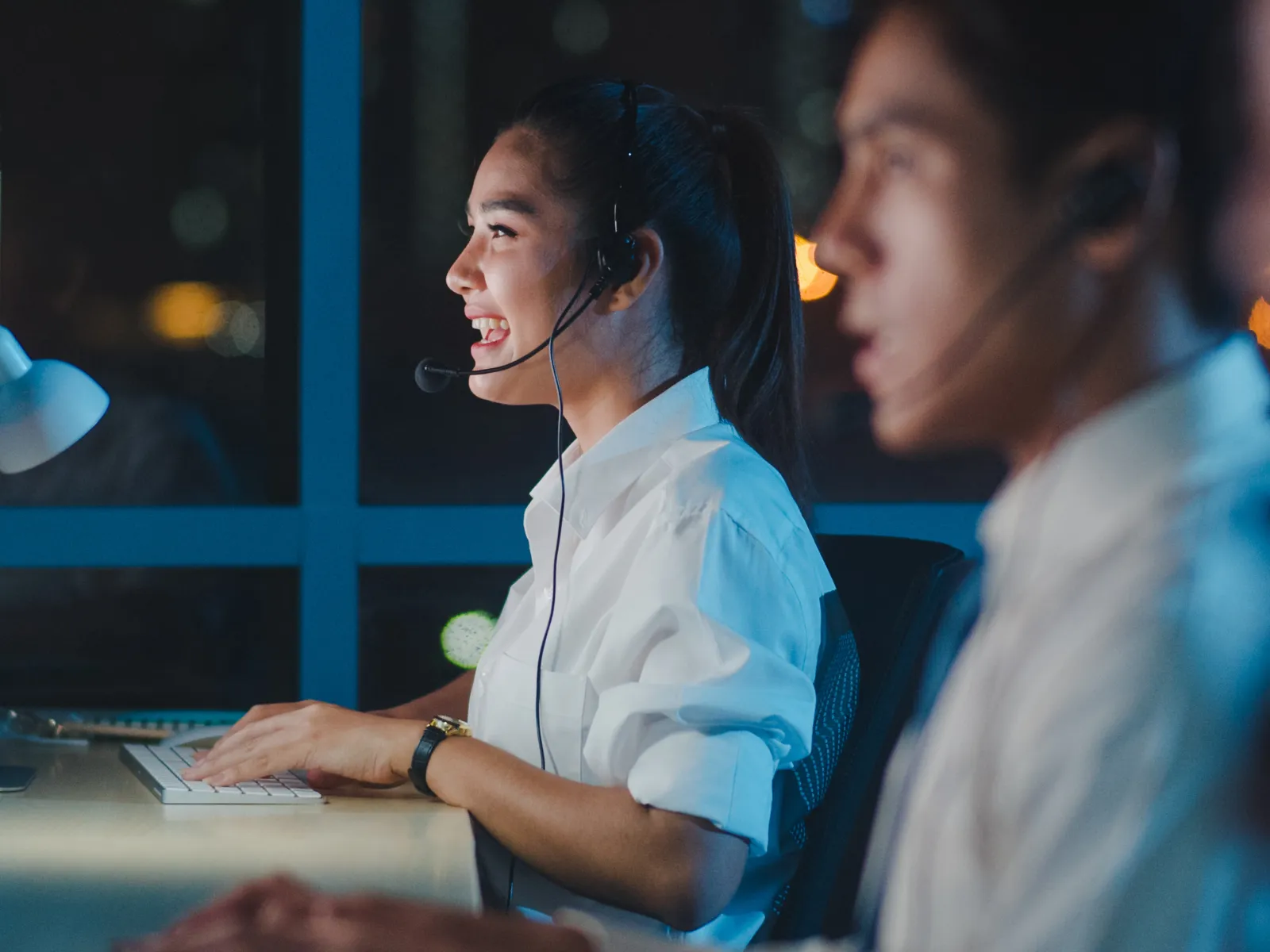 Customer service team working late at computer stations wearing headsets in a modern office environment