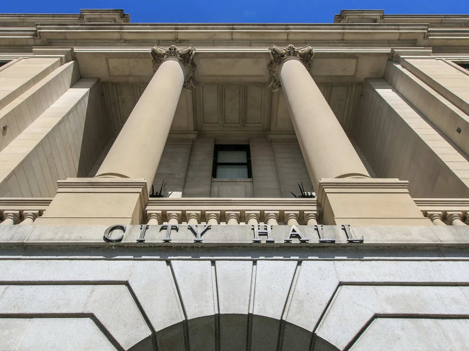 Low angle view of a neoclassical city hall building with tall columns and clear blue sky