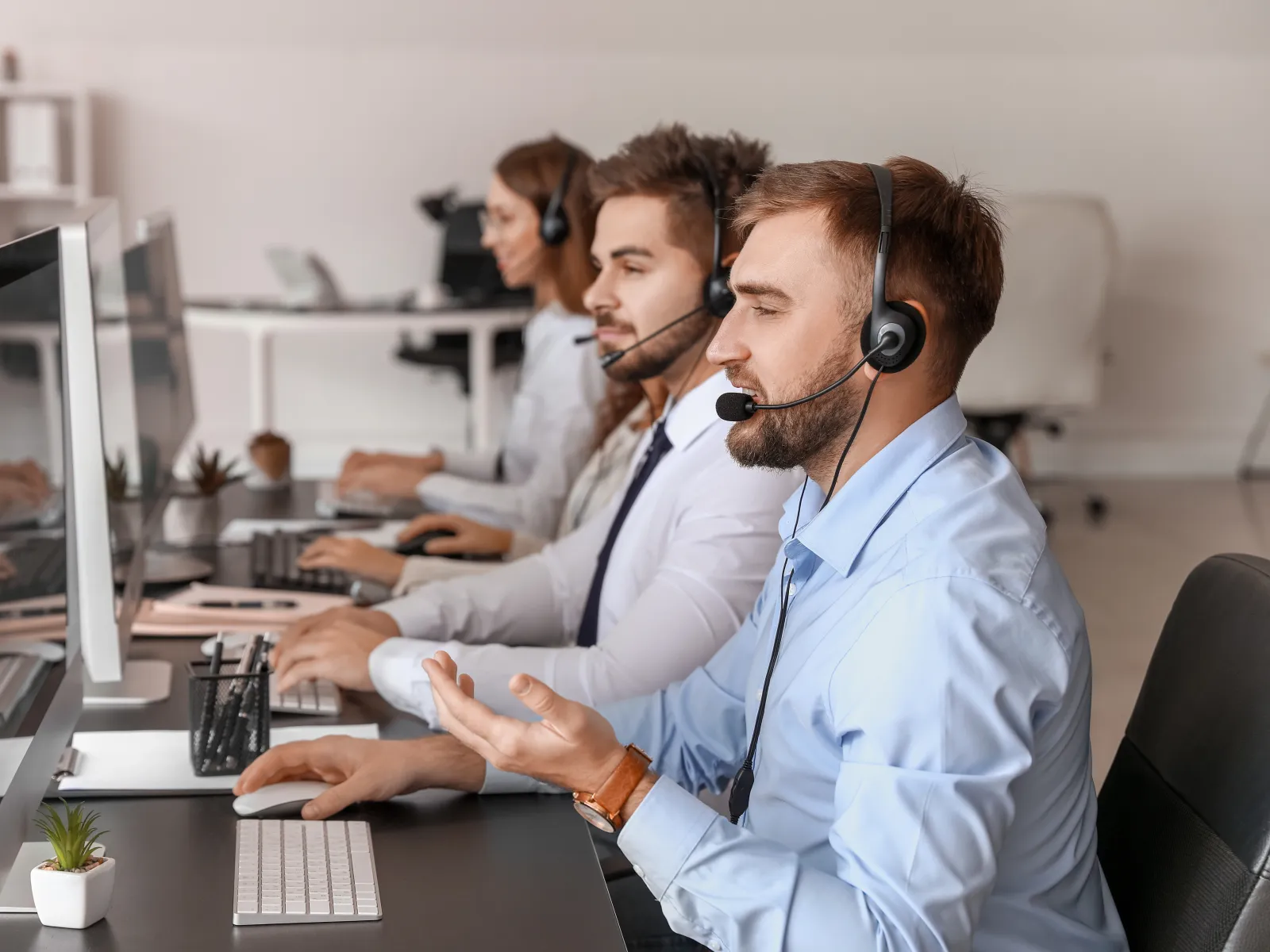 Customer support team wearing headsets working at computers in a modern office environment
