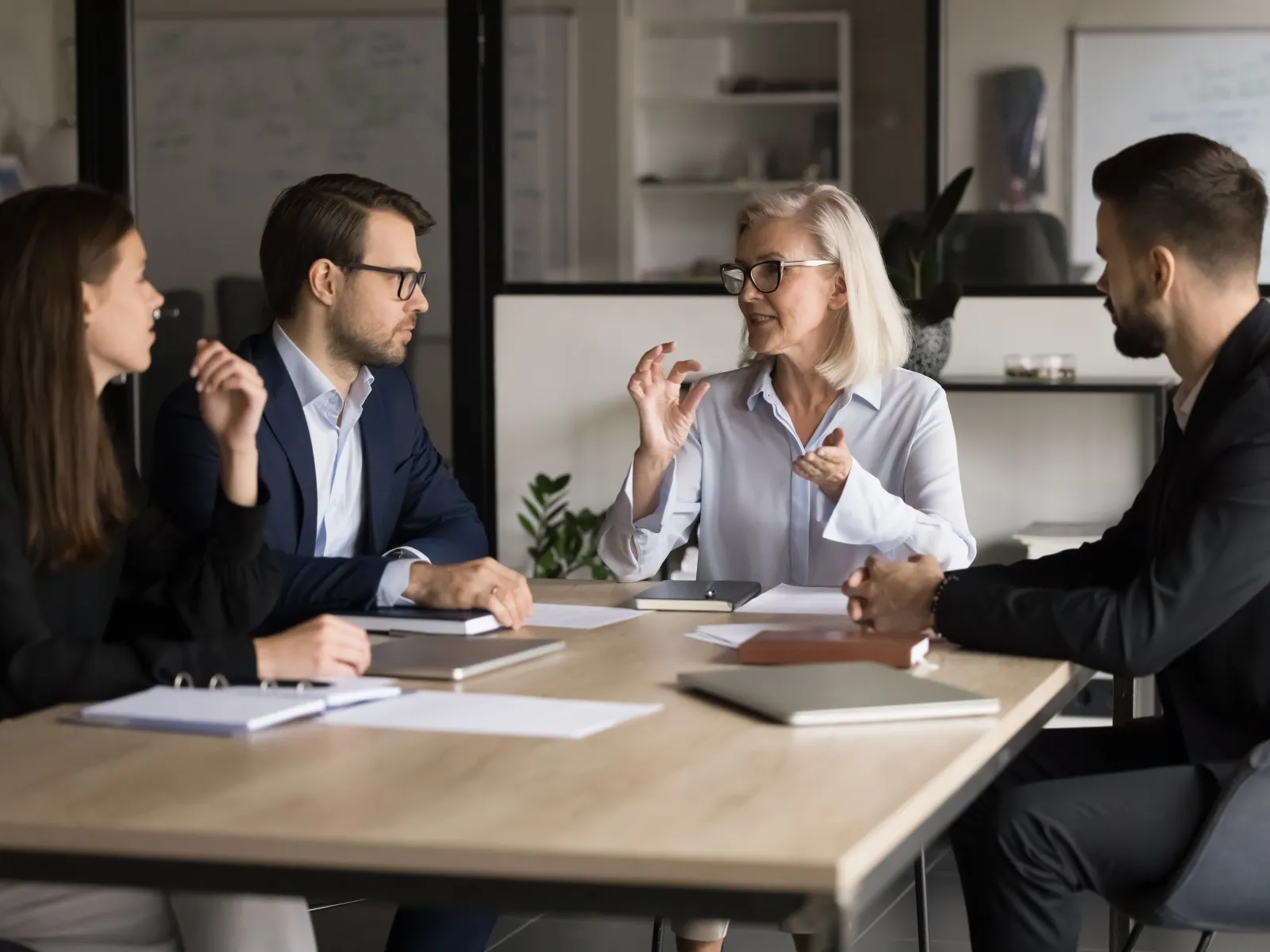 Business team in a meeting discussing strategies around a table in a modern office setting.