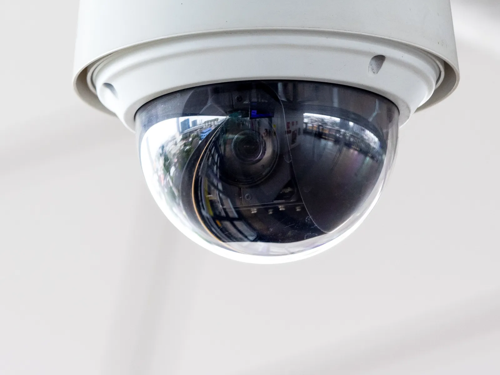 Close-up of a security camera lens, reflecting its surroundings in a modern setting.