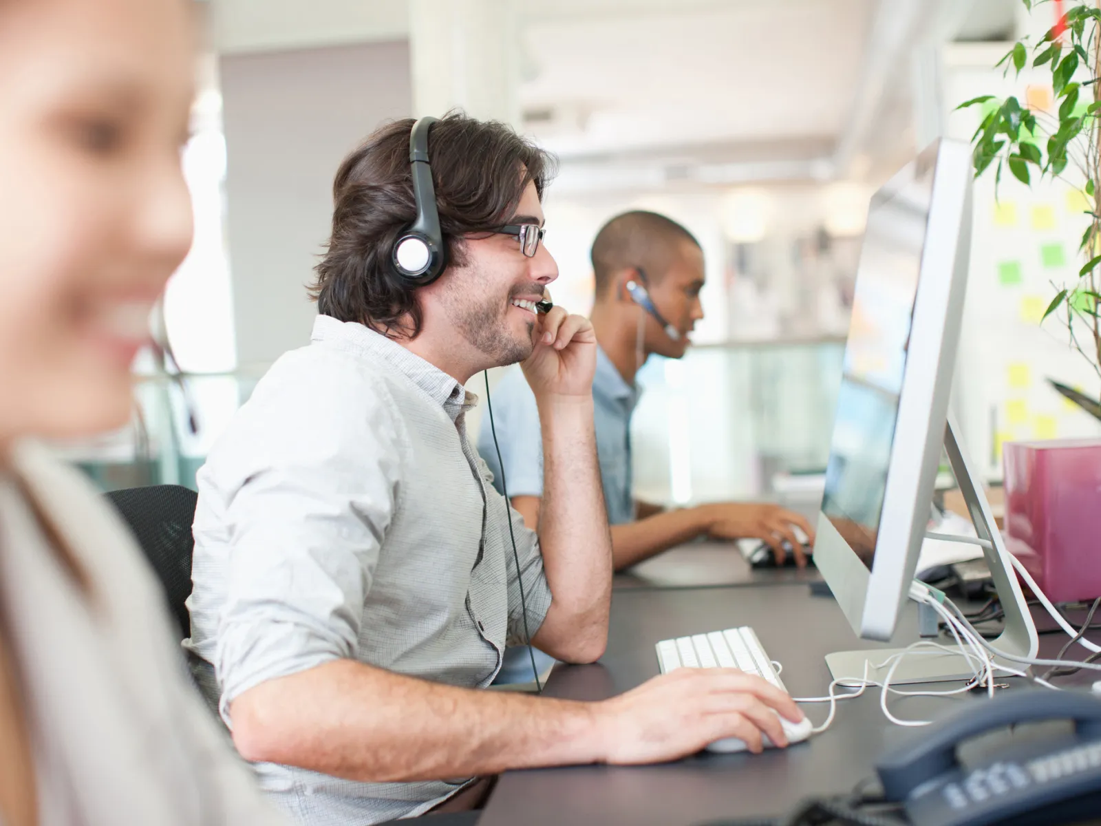 Customer service representatives wearing headsets working at computers in a modern office environment