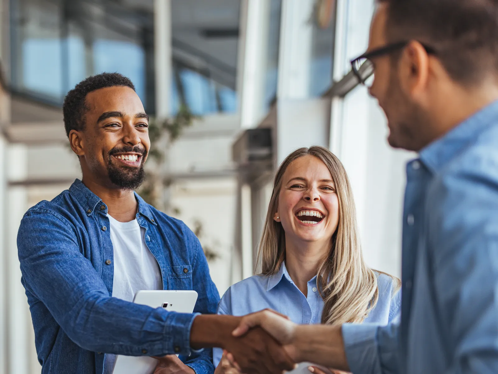 Smiling business colleagues shaking hands and discussing work in a bright modern office environment