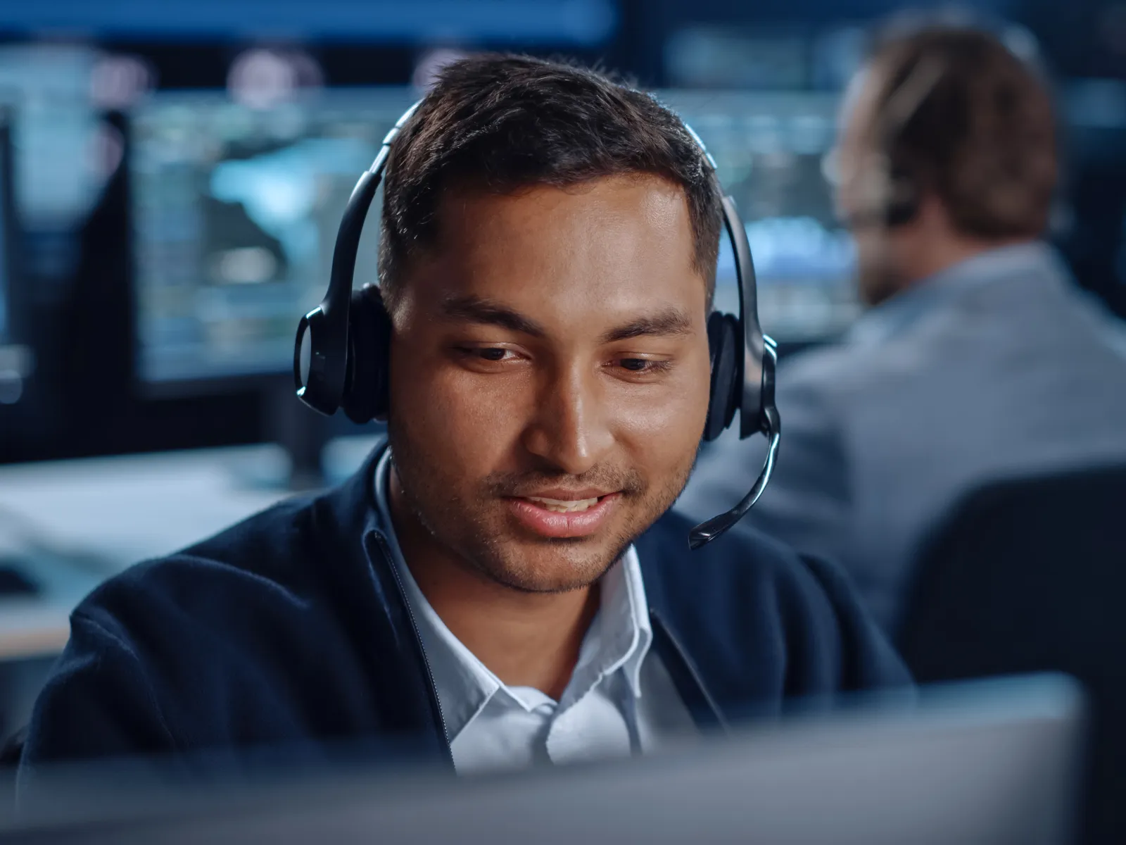 Customer support agent wearing headset working at computer in a busy call center environment