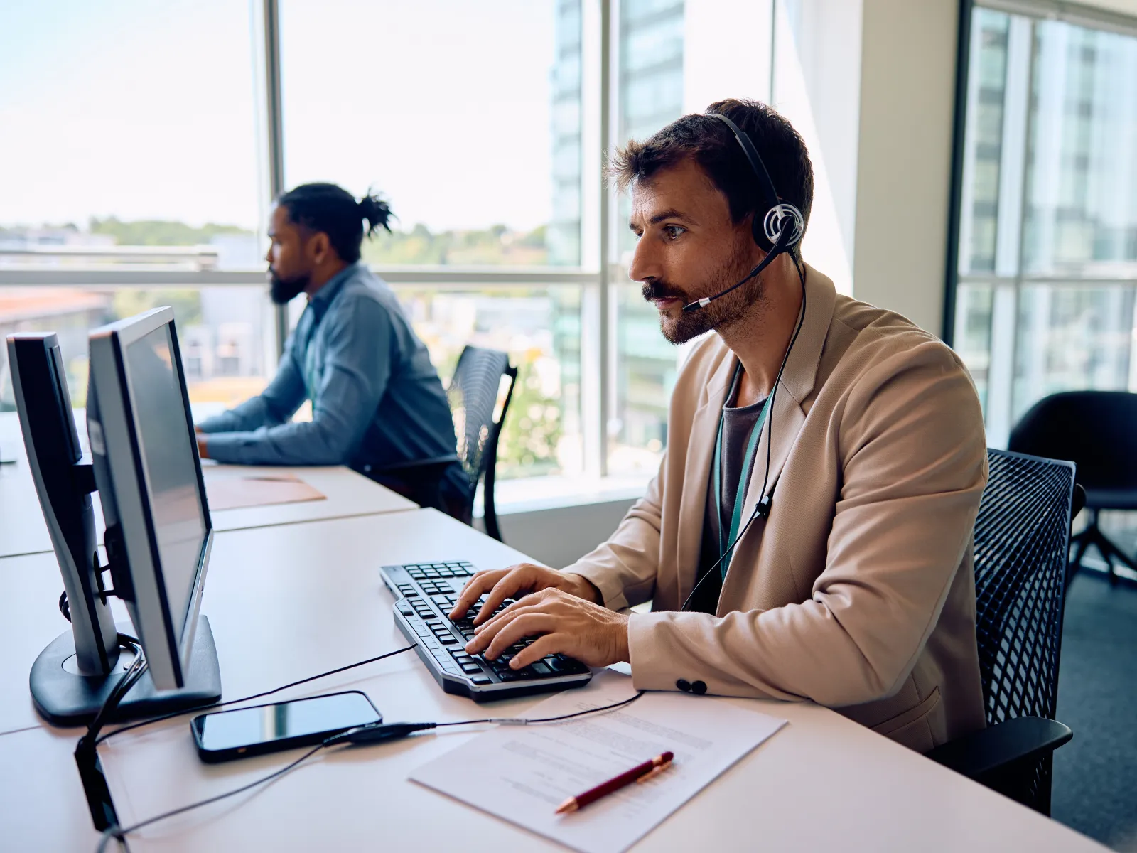 a person wearing headphones and sitting at a desk with a computer