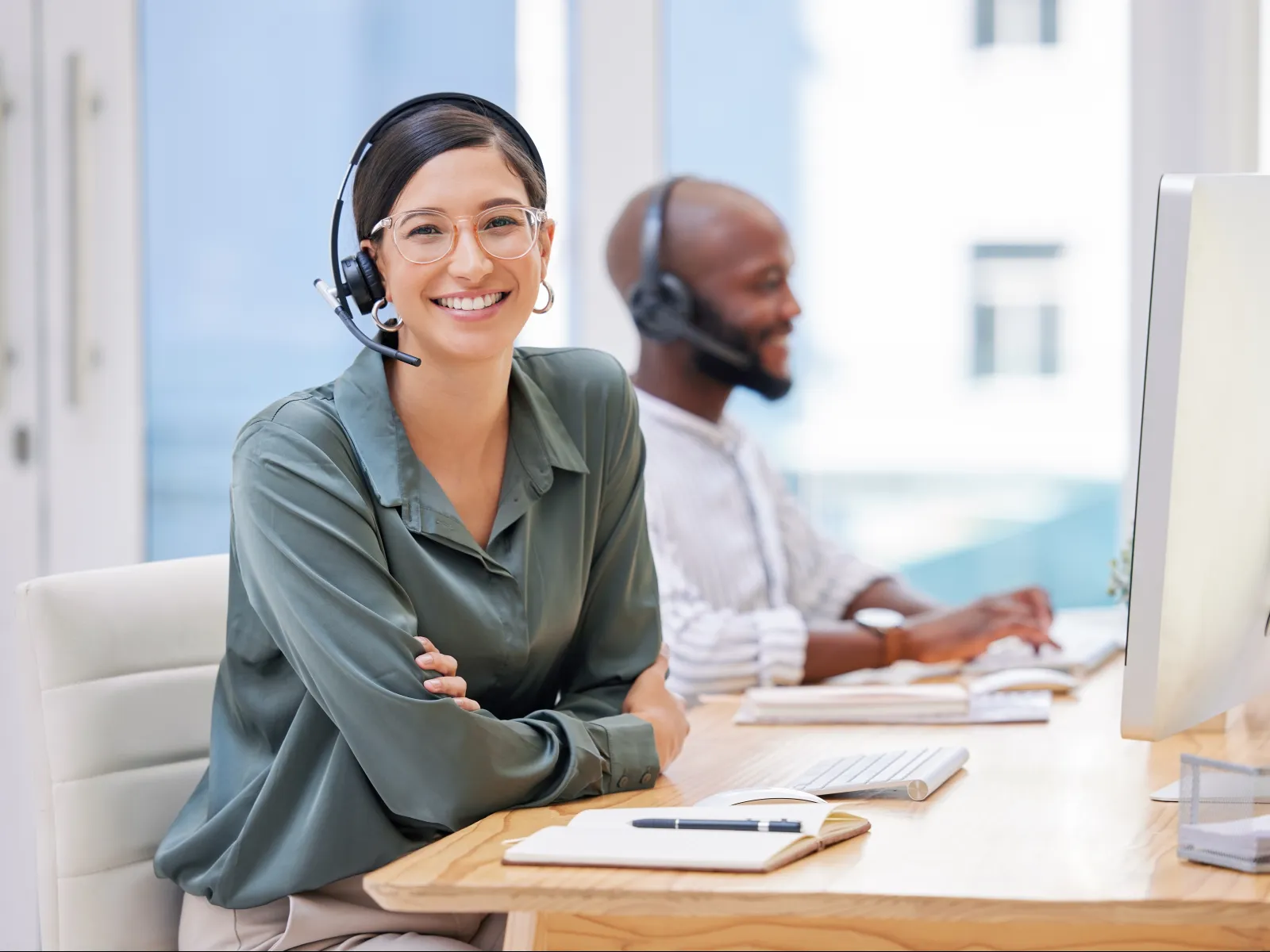 a man and a woman wearing headphones and sitting at a desk