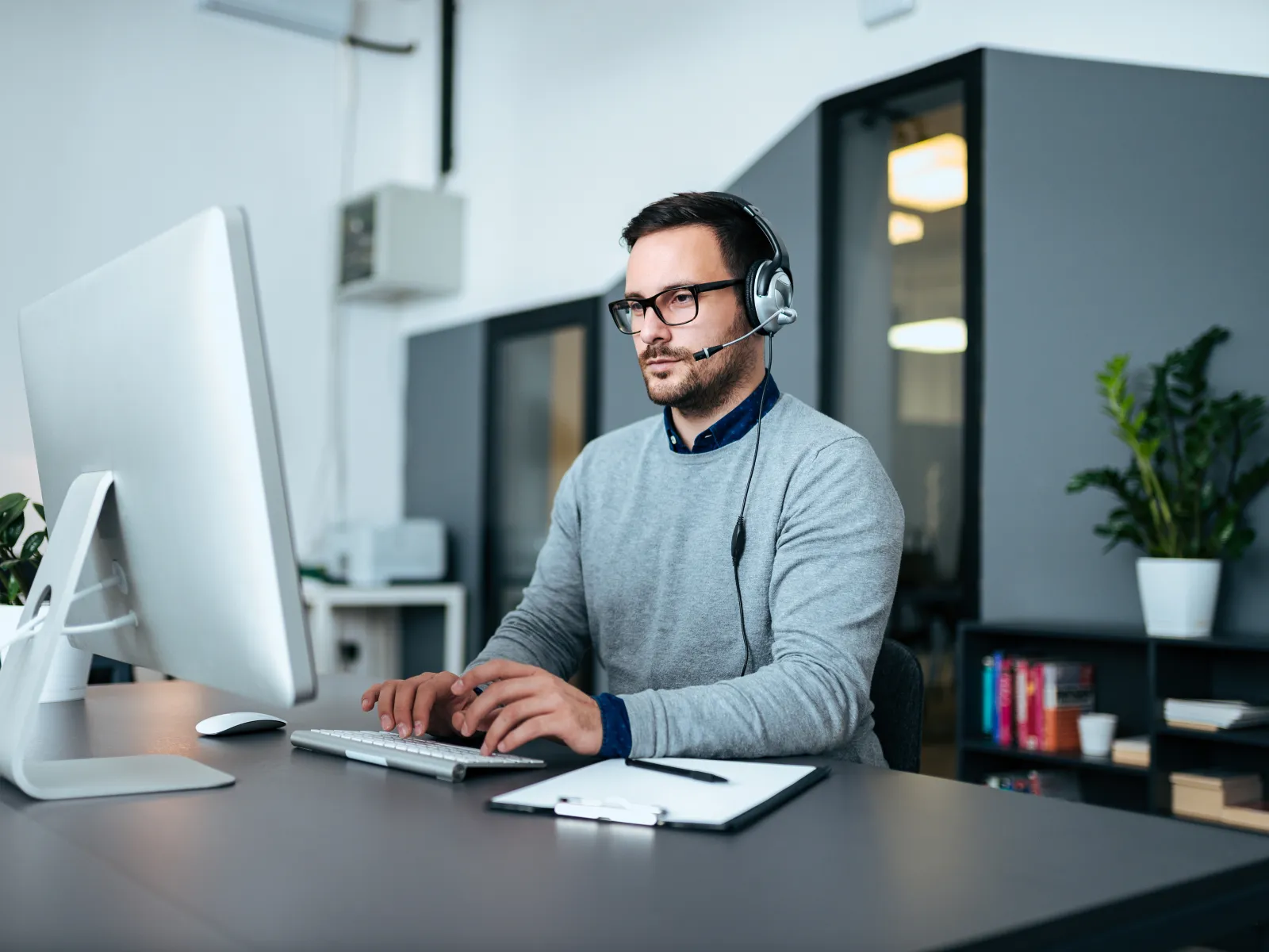 a man wearing headphones and sitting at a desk with a computer