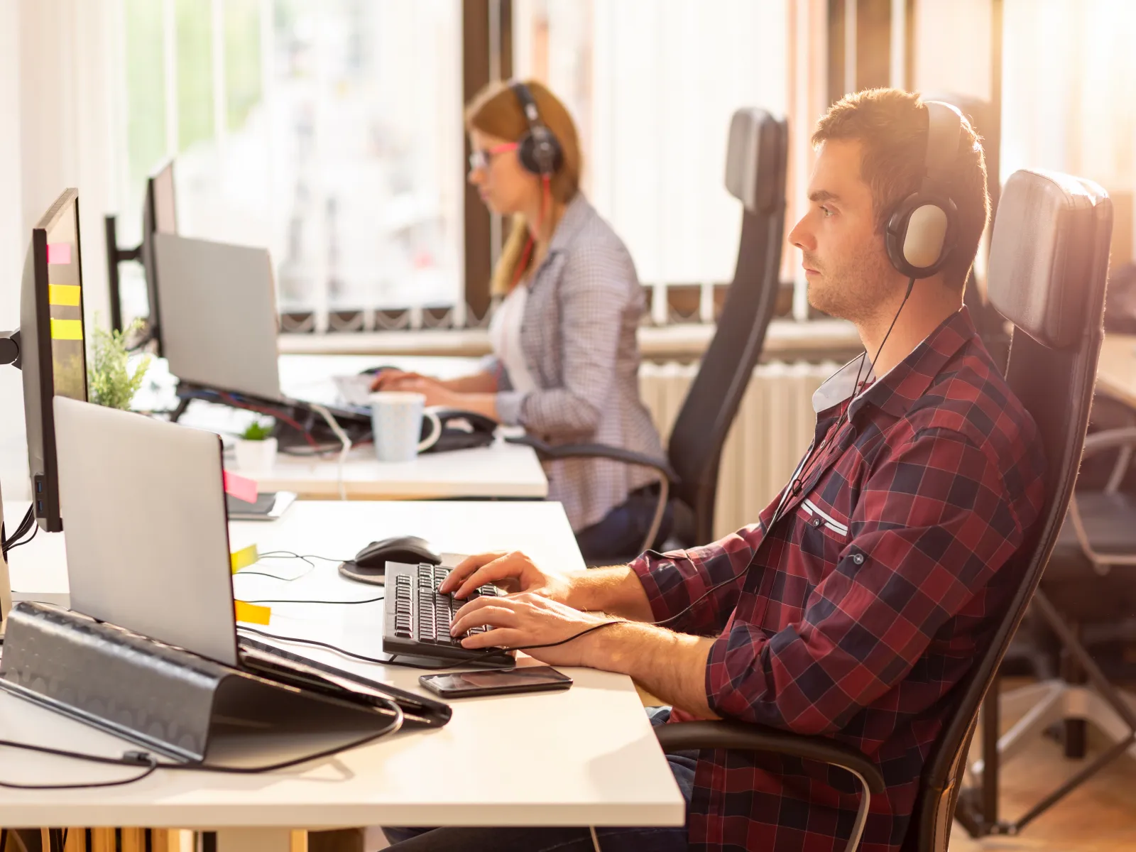 a man and a woman wearing headphones and sitting at a desk