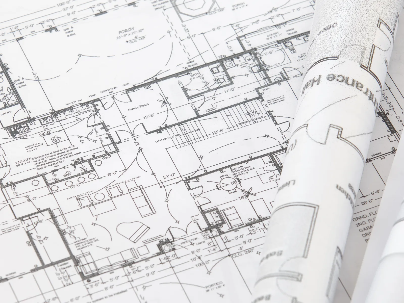 Detailed architectural floor plan with rolled blueprints showing rooms and structural layouts for a building project.