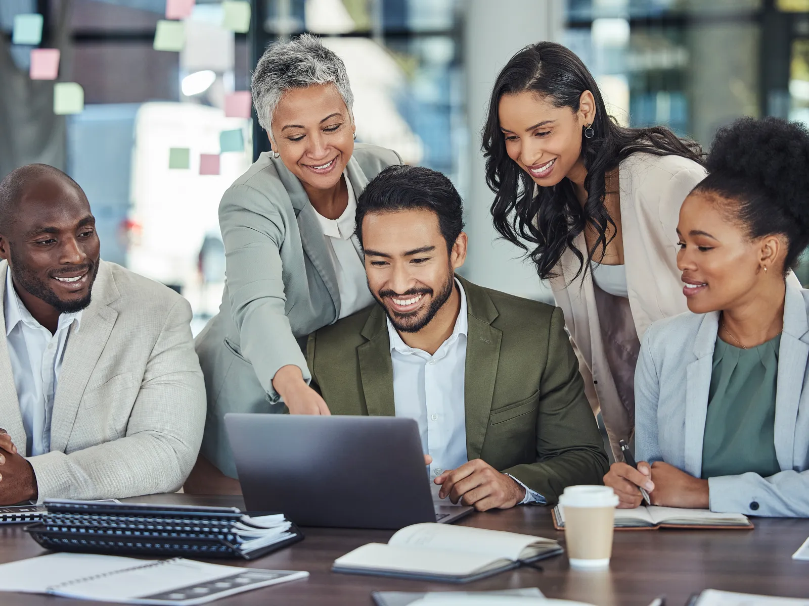 Diverse group of professionals collaborating at a laptop during a meeting.