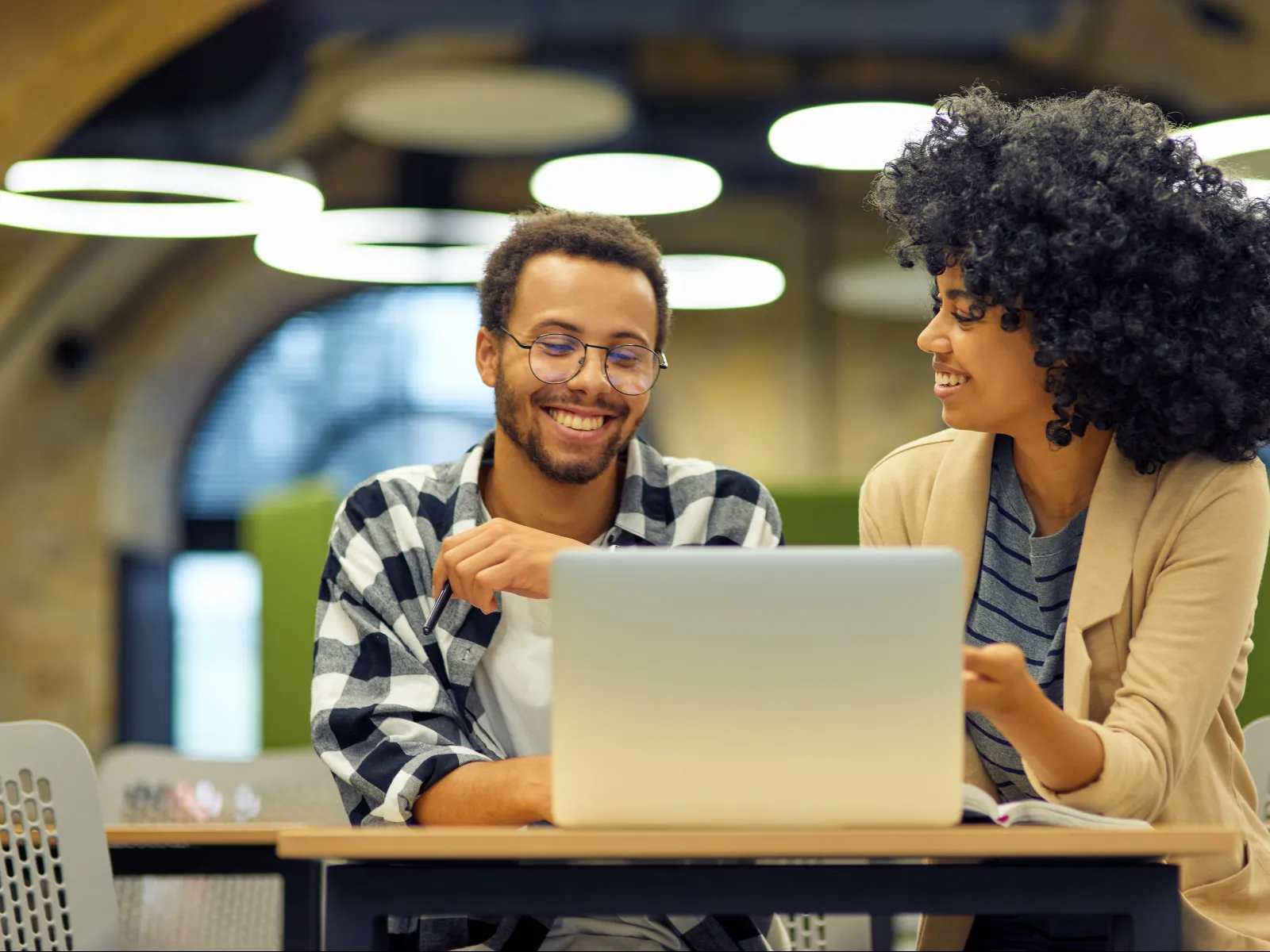 Two colleagues discussing ideas over a laptop in a modern office space.