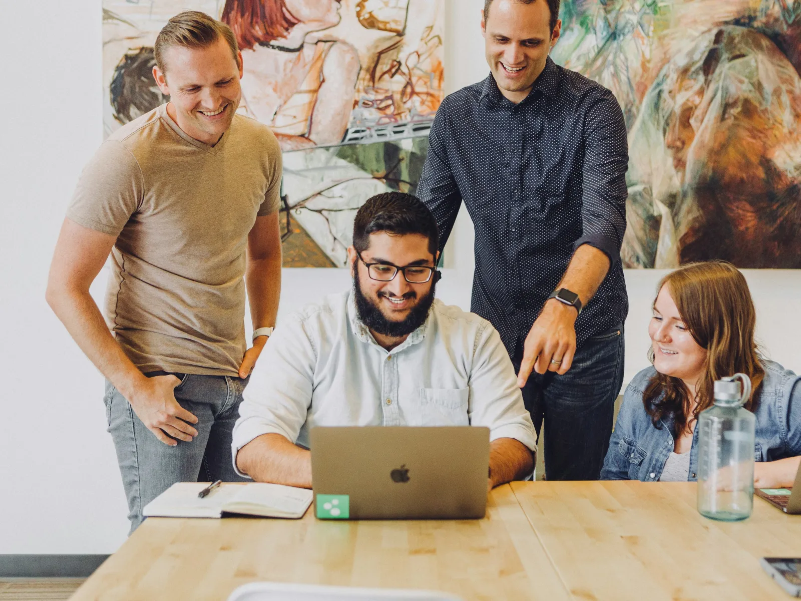 A diverse group of professionals collaborating over a laptop in a bright office space.