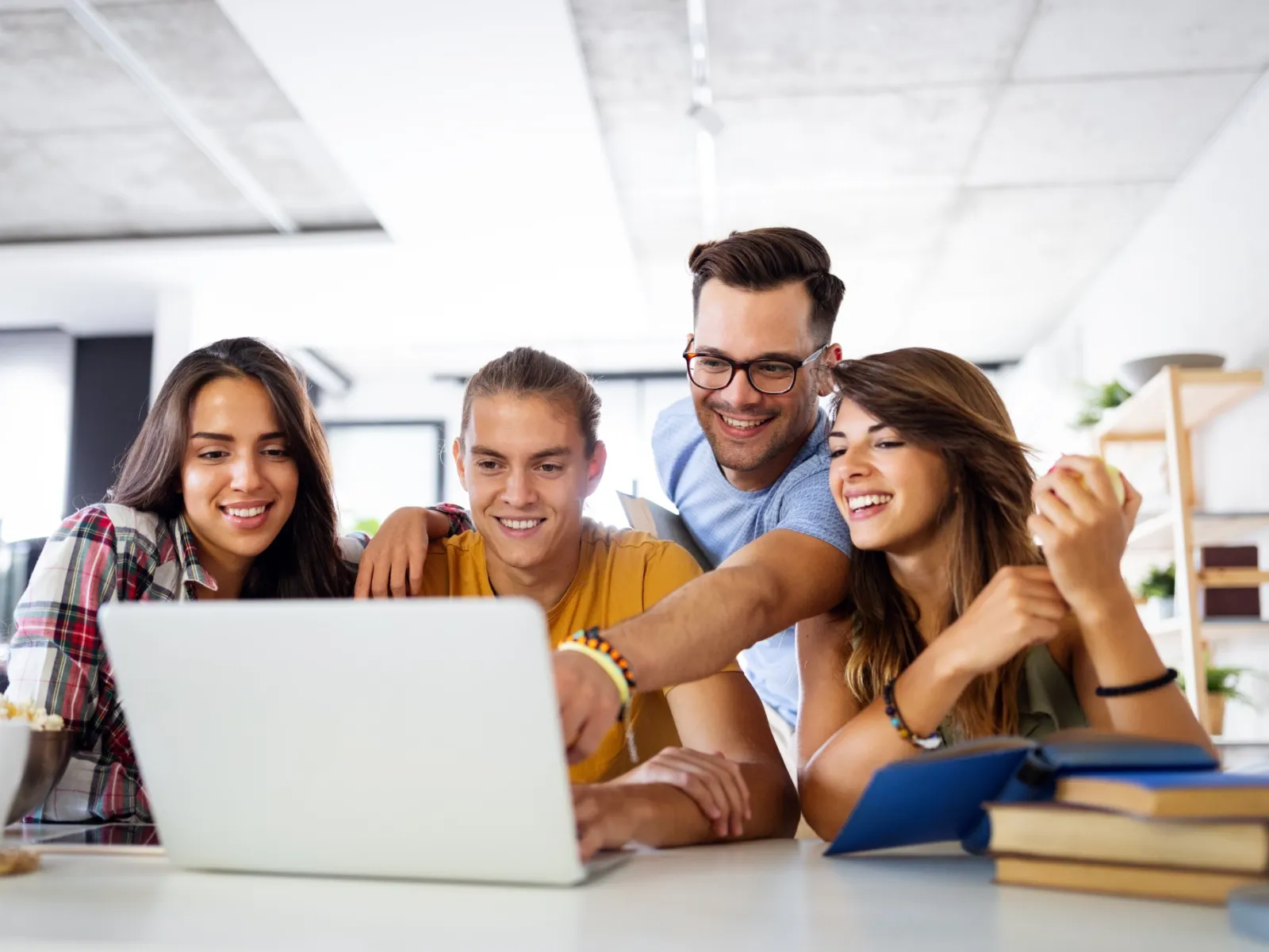 Group of friends collaborating over a laptop in a bright, modern workspace.