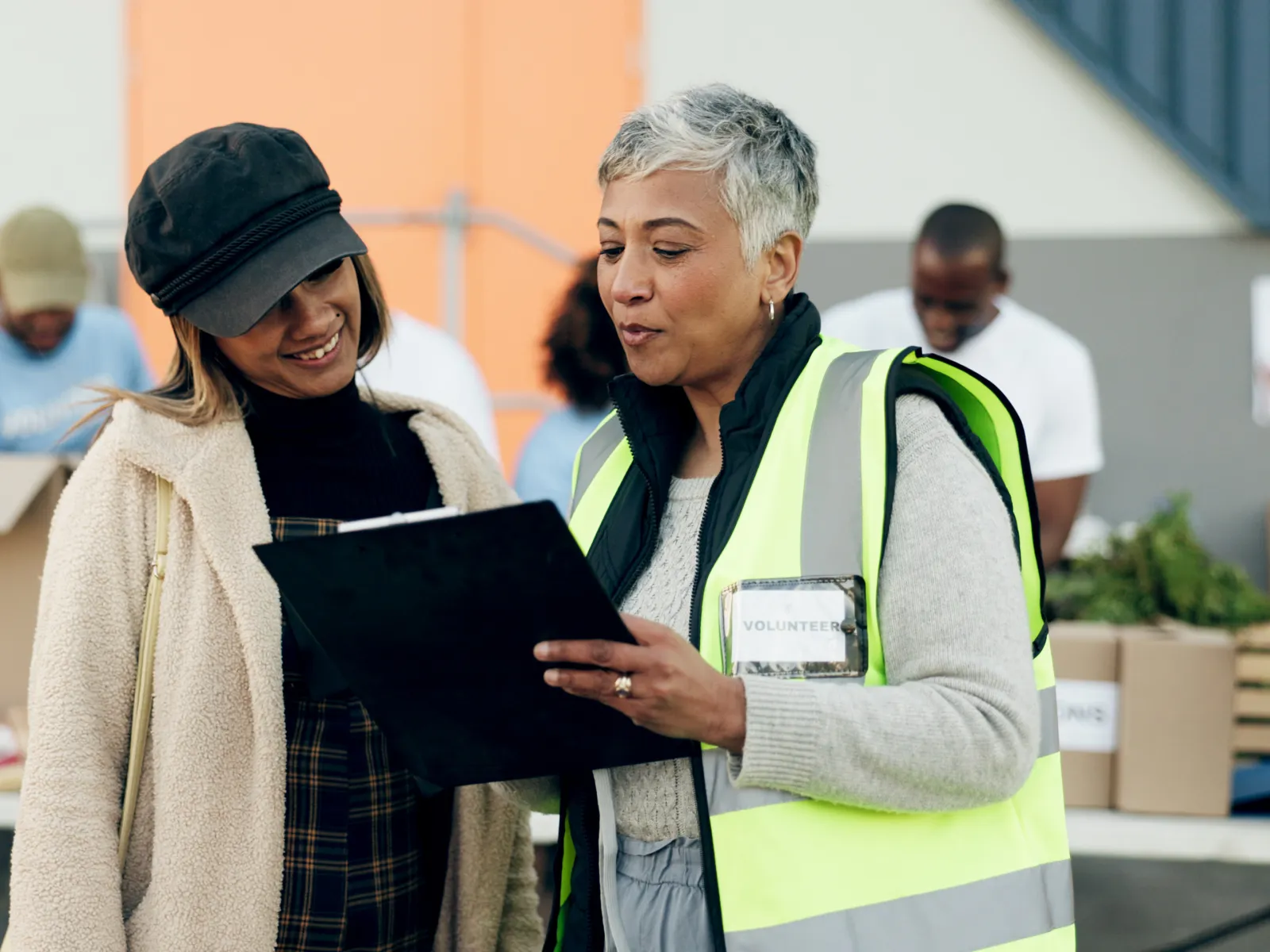Two women engaging in conversation at a community volunteer event with food donations.