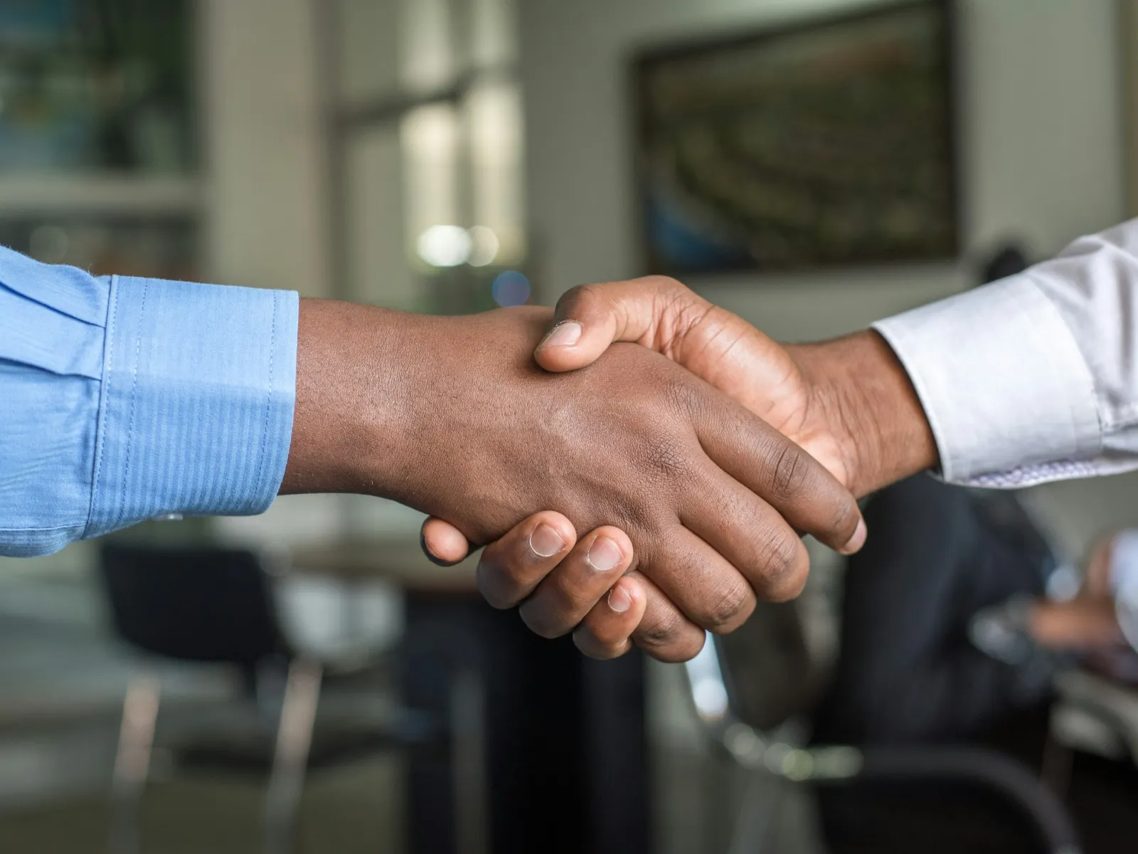 Close-up of two people shaking hands in a professional office setting symbolizing agreement and partnership.
