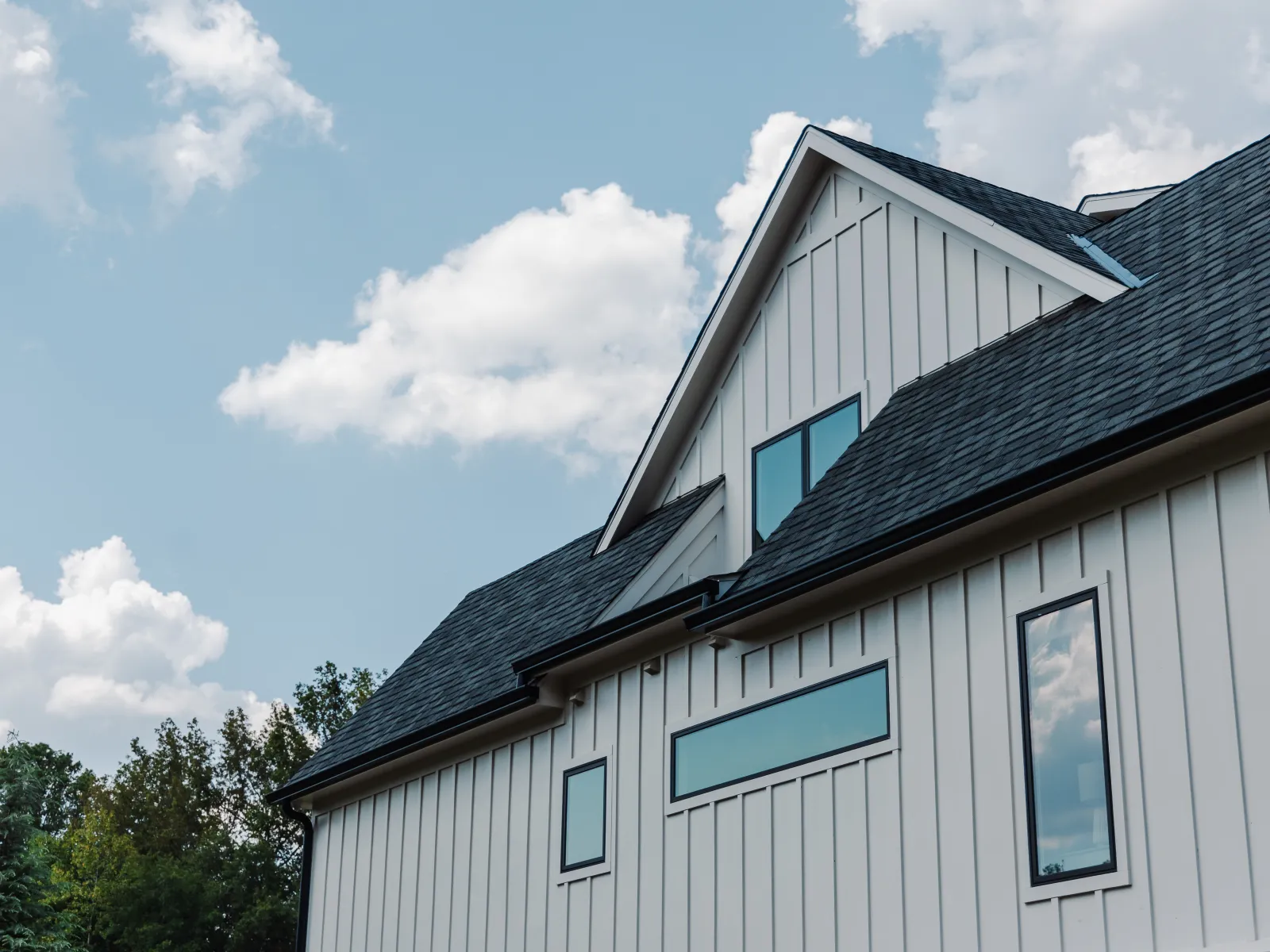 A white home with board and batten siding and black fiberglass Infinity windows with energy efficient Low E3 glass.