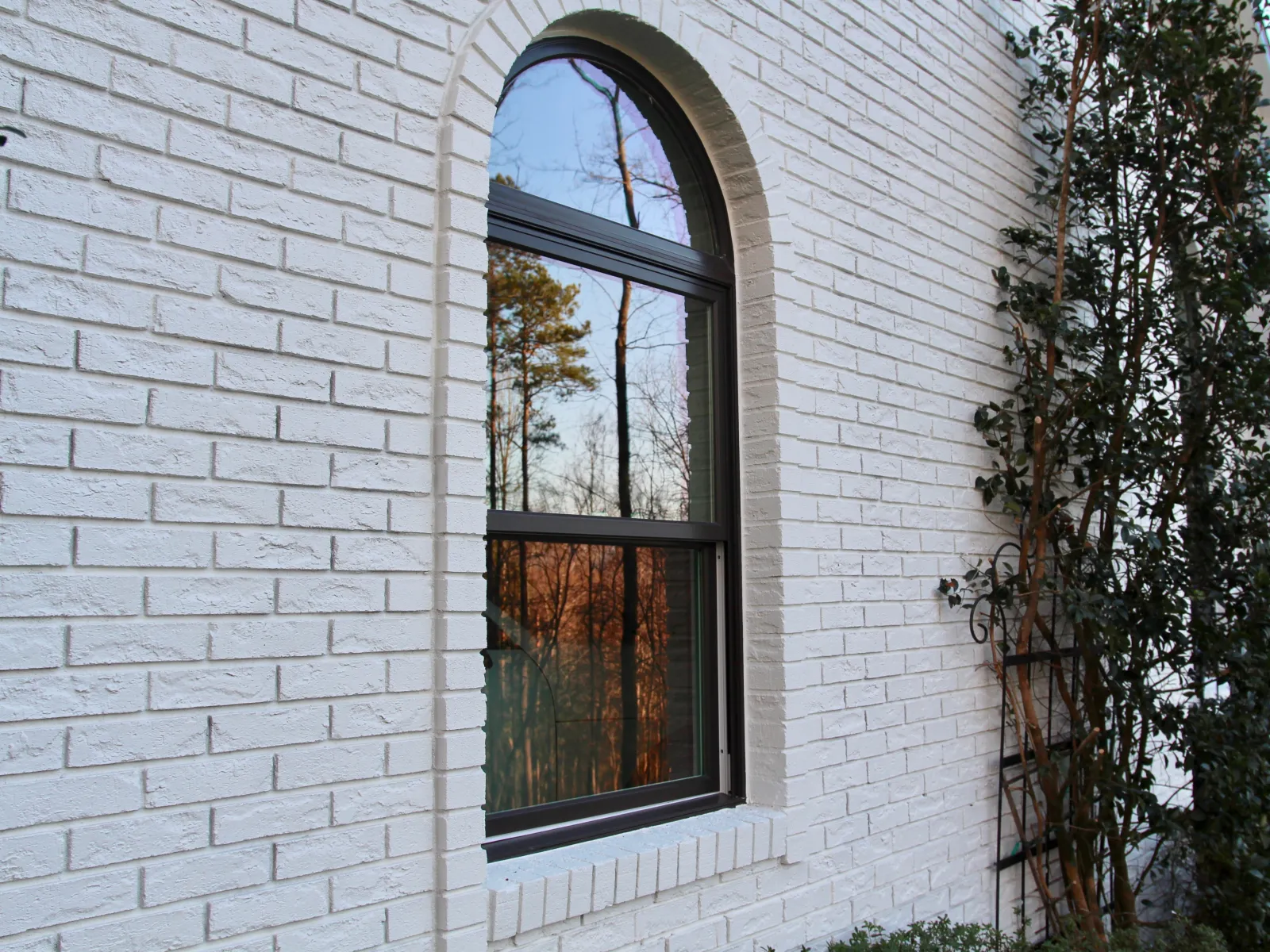 Infinity round top window replacement installed in white brick house