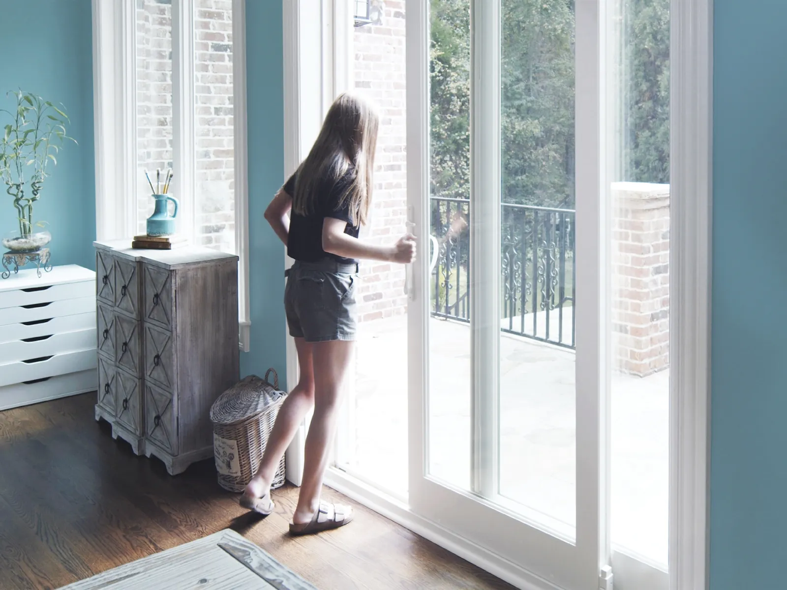A young woman opening sliding French doors to access balcony
