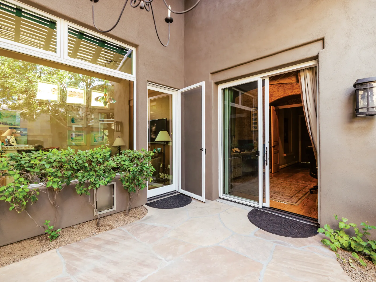 A serene outdoor patio with glass doors, green plants, and warm lighting in a modern home setting.