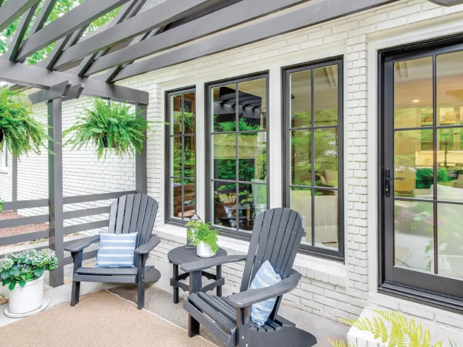 Professionally designed by Georgia's premier window installation contractor resulted in this beautiful patio with black chairs, pergola, and modern black fiberglass windows and patio door on this white brick house